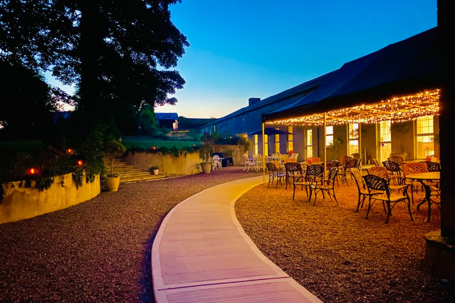 Outdoor evening view of a venue with lit pathways and elegant seating.