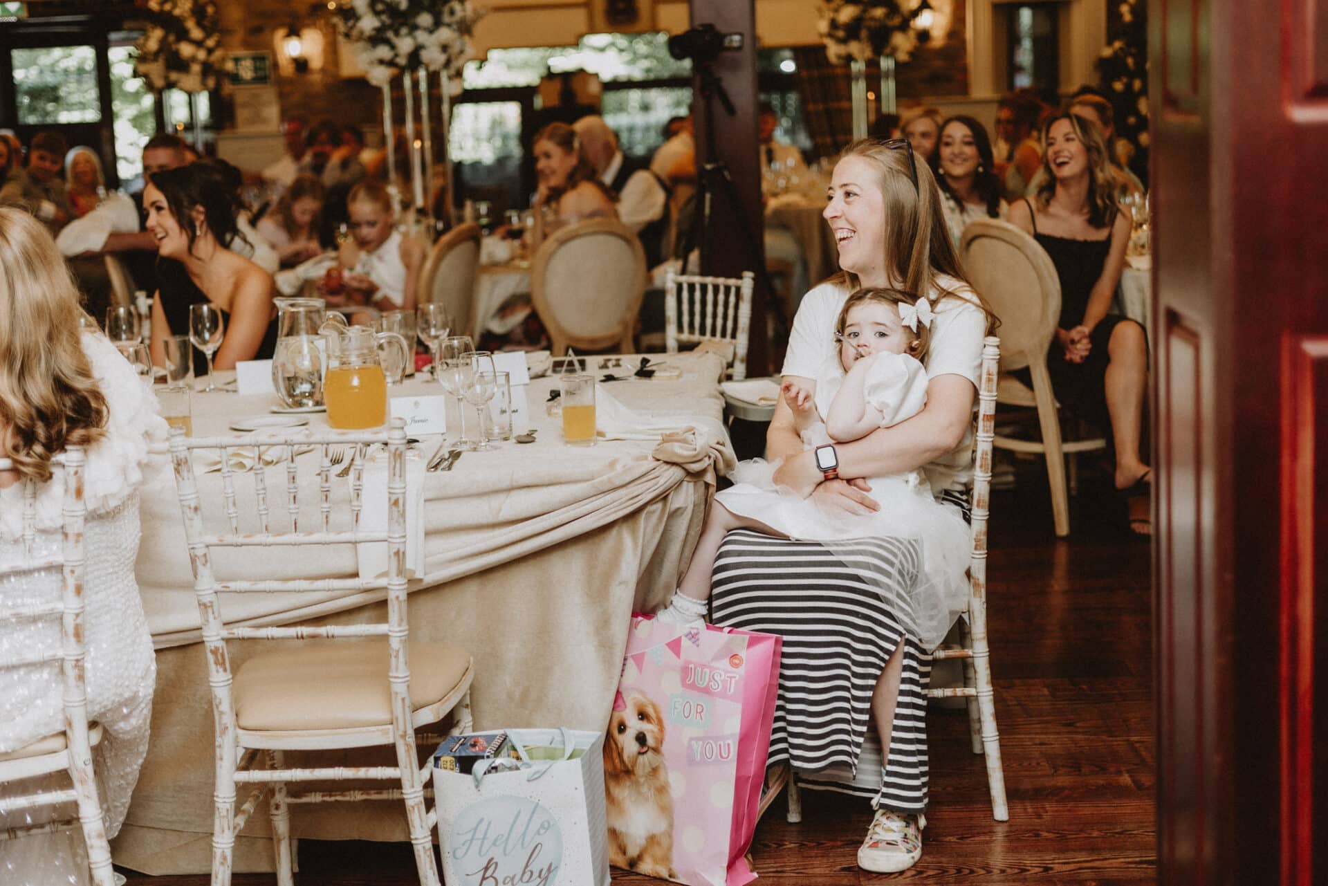Nanny Cat cuddles Natalie & Stephens youngest daughter during the wedding breakfast as guests enjoy the celebrations around them