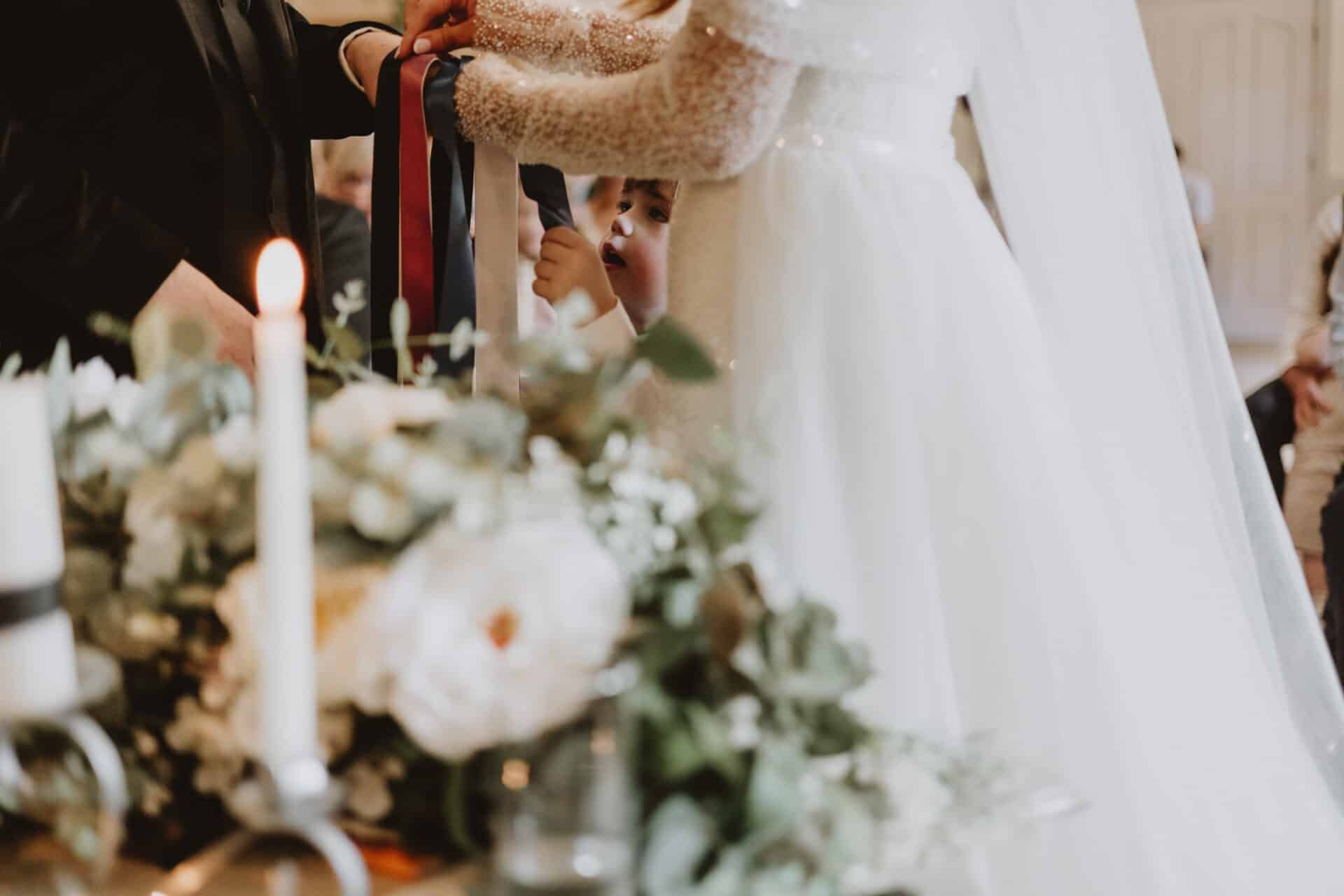 Natalie and Stephen take part in a ribbon-tying ceremony with the help of their little ones during their family-focused wedding ceremony at Darver Castle.