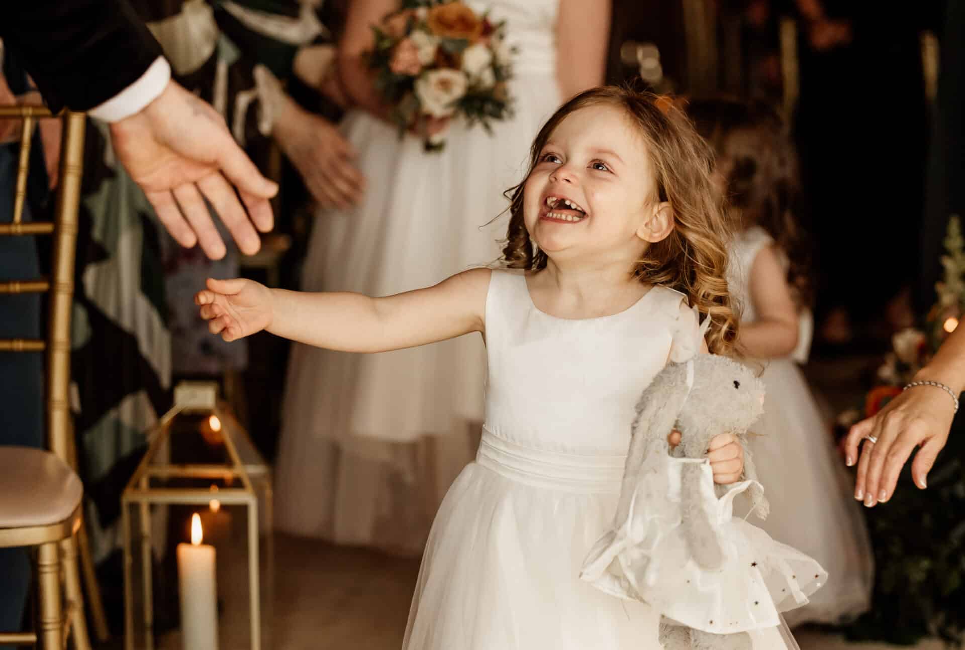 Flower girl smiling with joy after walking down the aisle to her dad at a Northern Ireland wedding ceremony.