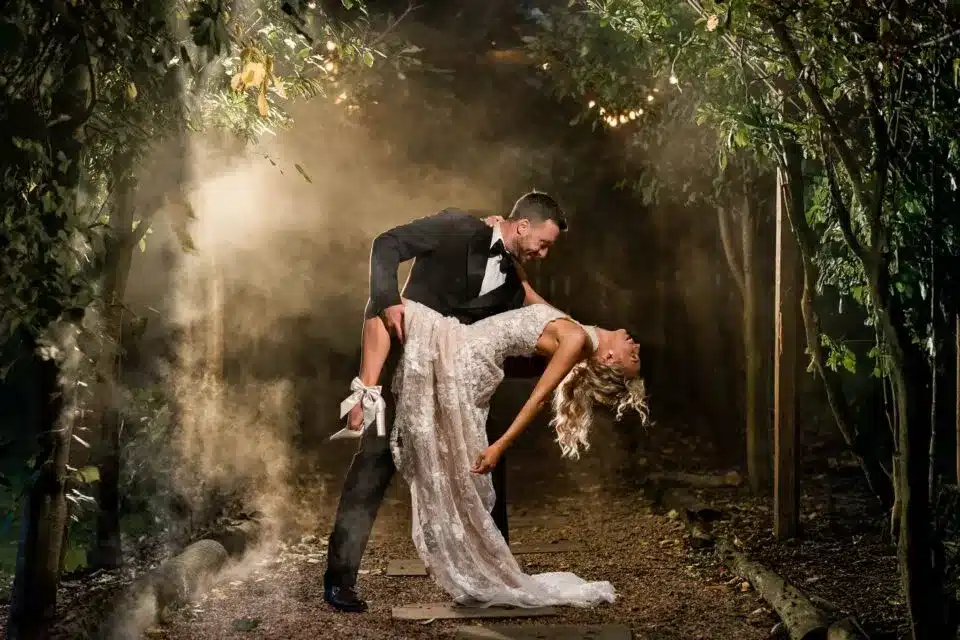 Bride and groom dancing outdoors in dramatic lighting, featured in vendor listing card.