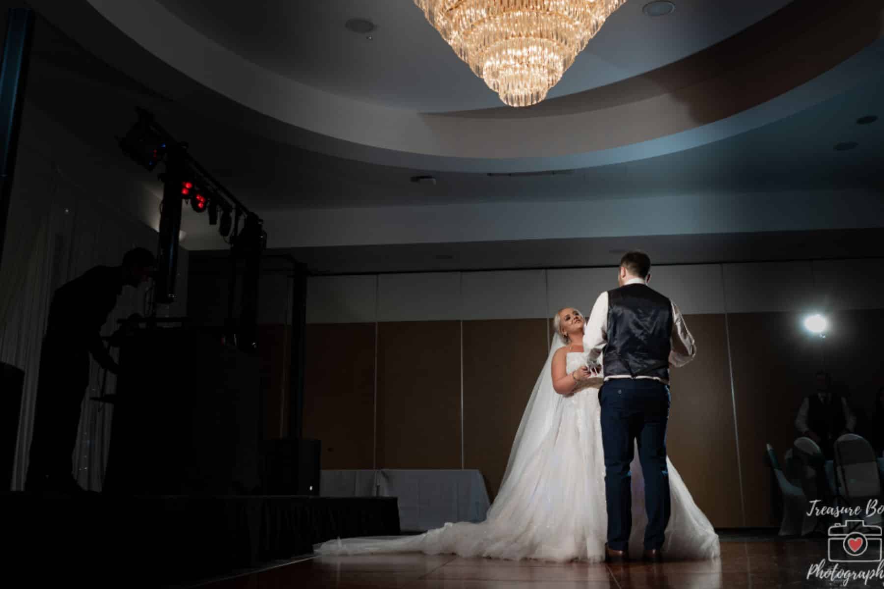 Bride and groom dancing under a chandelier at La Mon Hotel & Country Club.