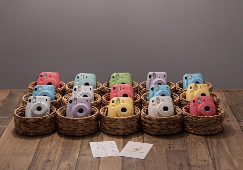 Colorful instant cameras in wicker baskets displayed on a wooden surface.