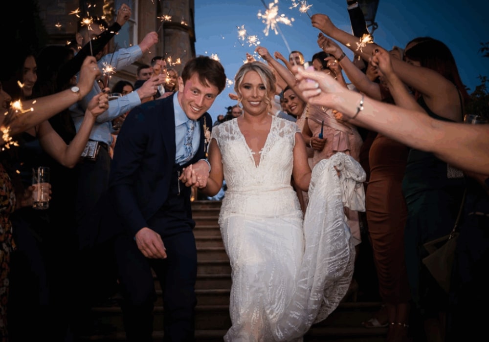Bride and groom exit wedding ceremony with sparklers and guests.