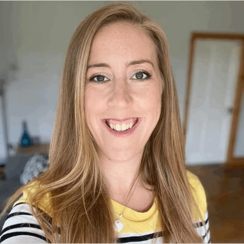 Smiling woman with long hair wearing a striped top indoors.