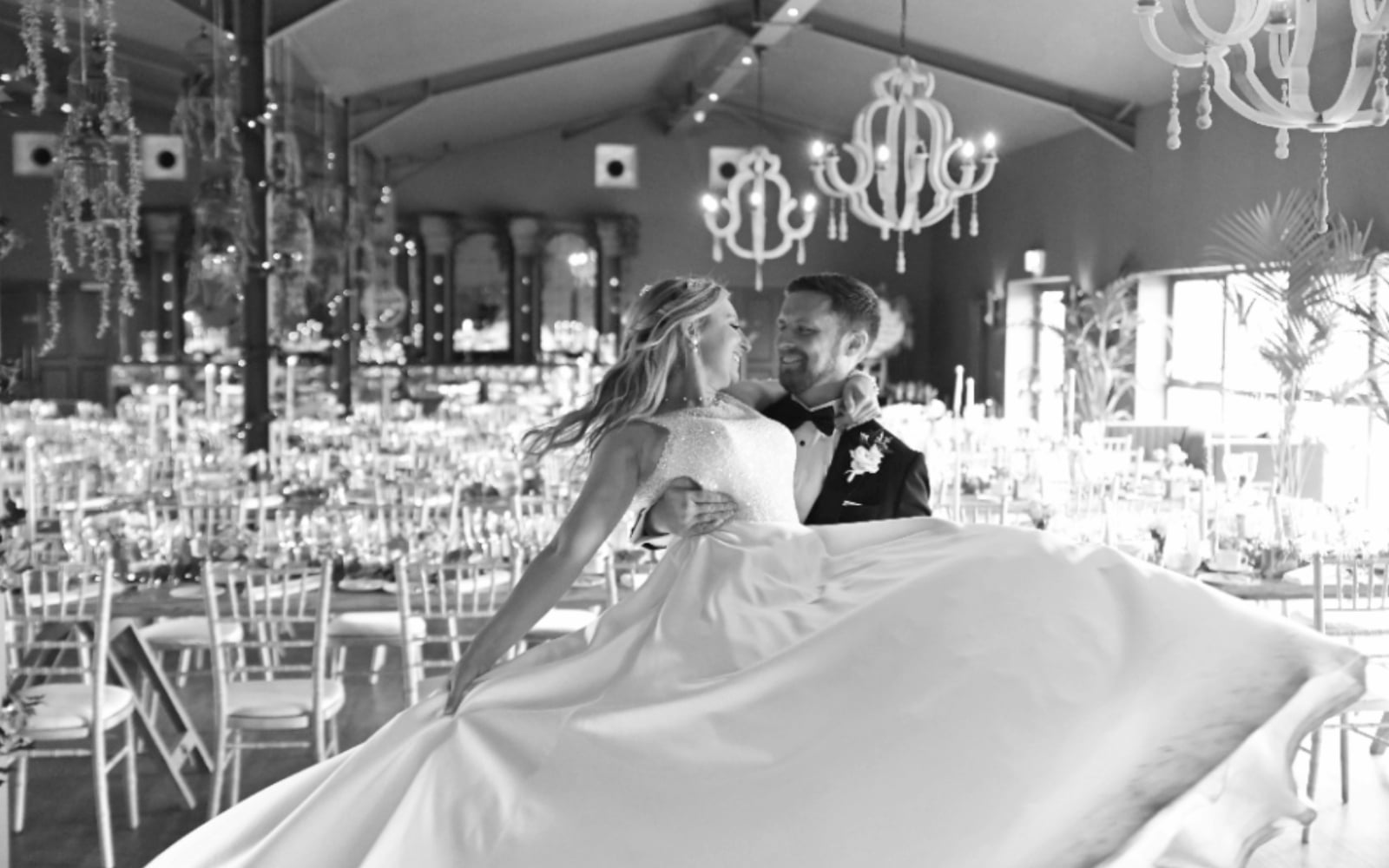 Bride and groom dancing joyfully in an elegant, decorated venue.