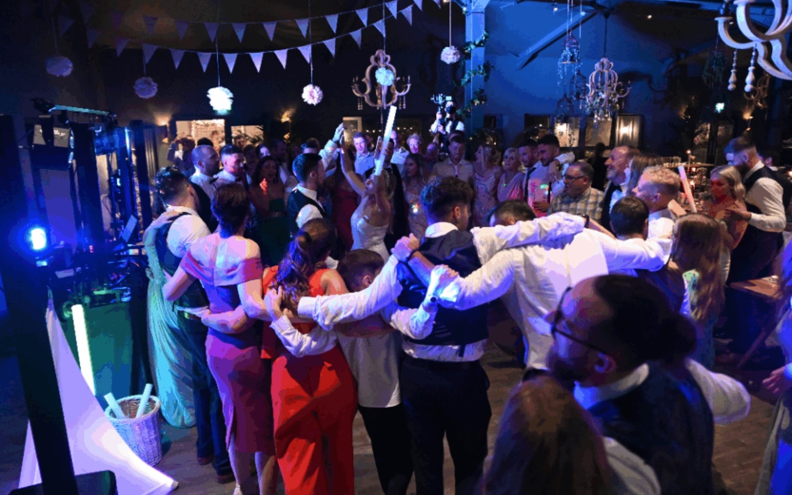 Group of people dancing and celebrating at a festive event, under colorful lights and decorations.