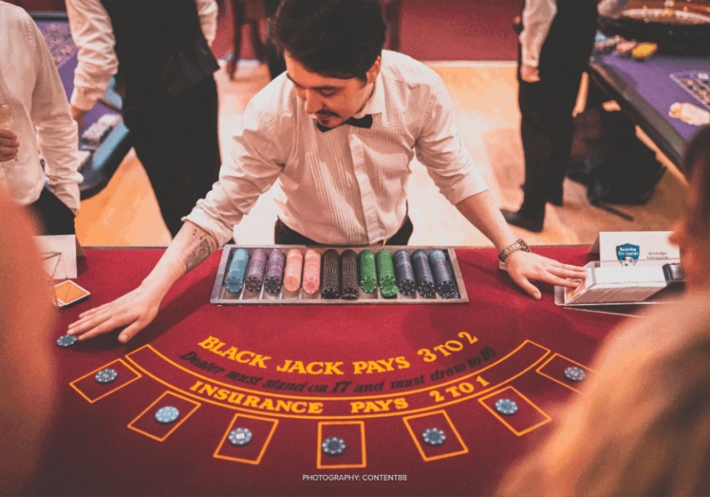 Dealer managing a blackjack table at a casino with colorful chips.