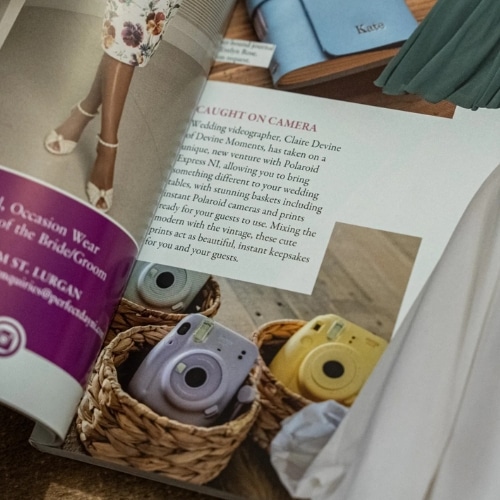 Open magazine showing a page with instant cameras in baskets and a person in floral attire wearing heels.