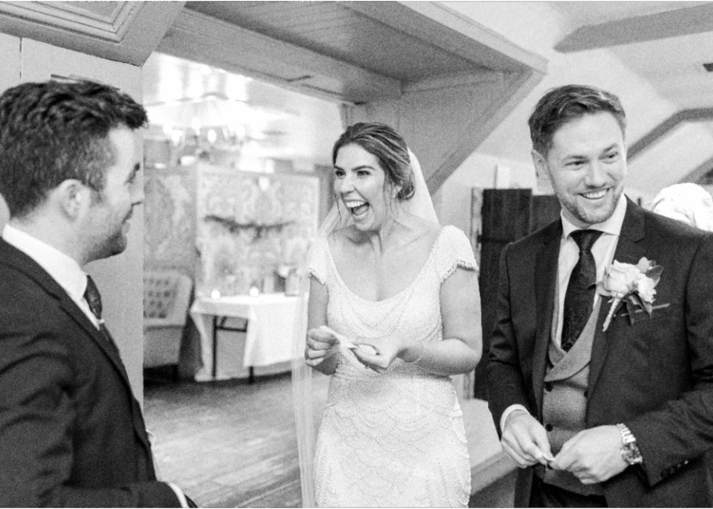 Bride laughing with two groomsmen at a wedding reception.