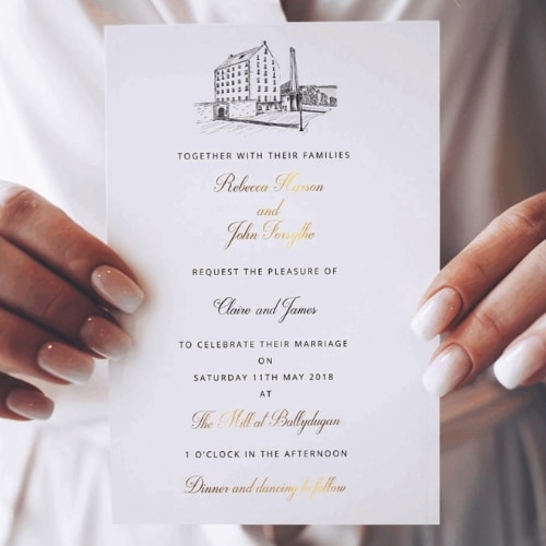 Wedding invitation held by hands, featuring elegant script and classic design.