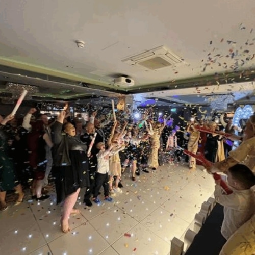 People celebrating indoors with confetti and party poppers.