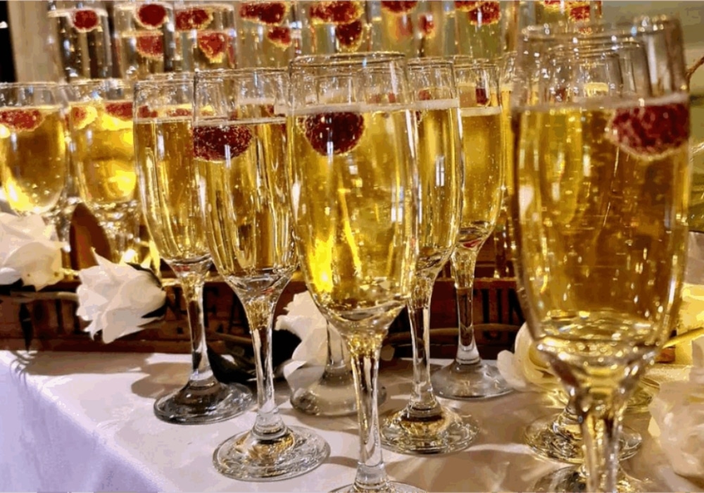 Glasses of champagne with raspberries on a decorated table.