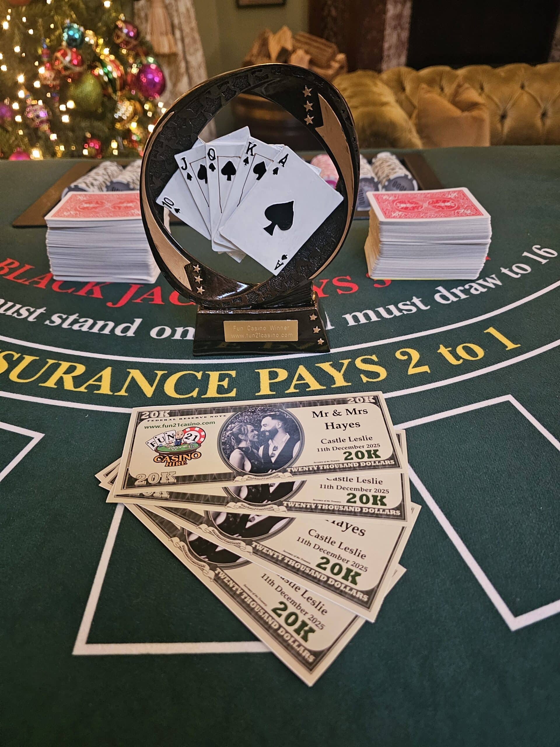 Poker trophy and mock casino money on a table with festive decorations in the background.