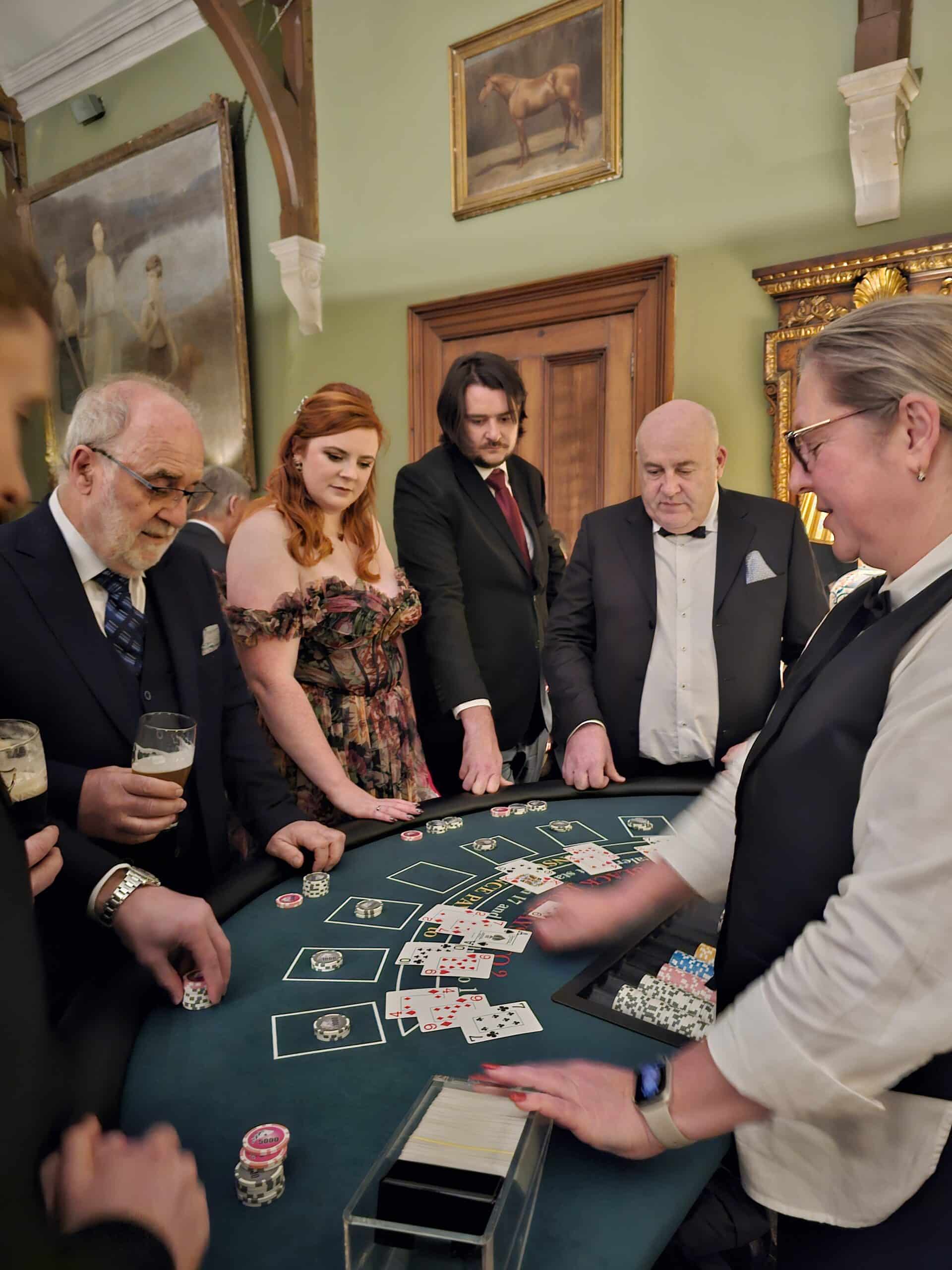 People playing poker at a casino table, dressed in formal attire, with a dealer managing the game.
