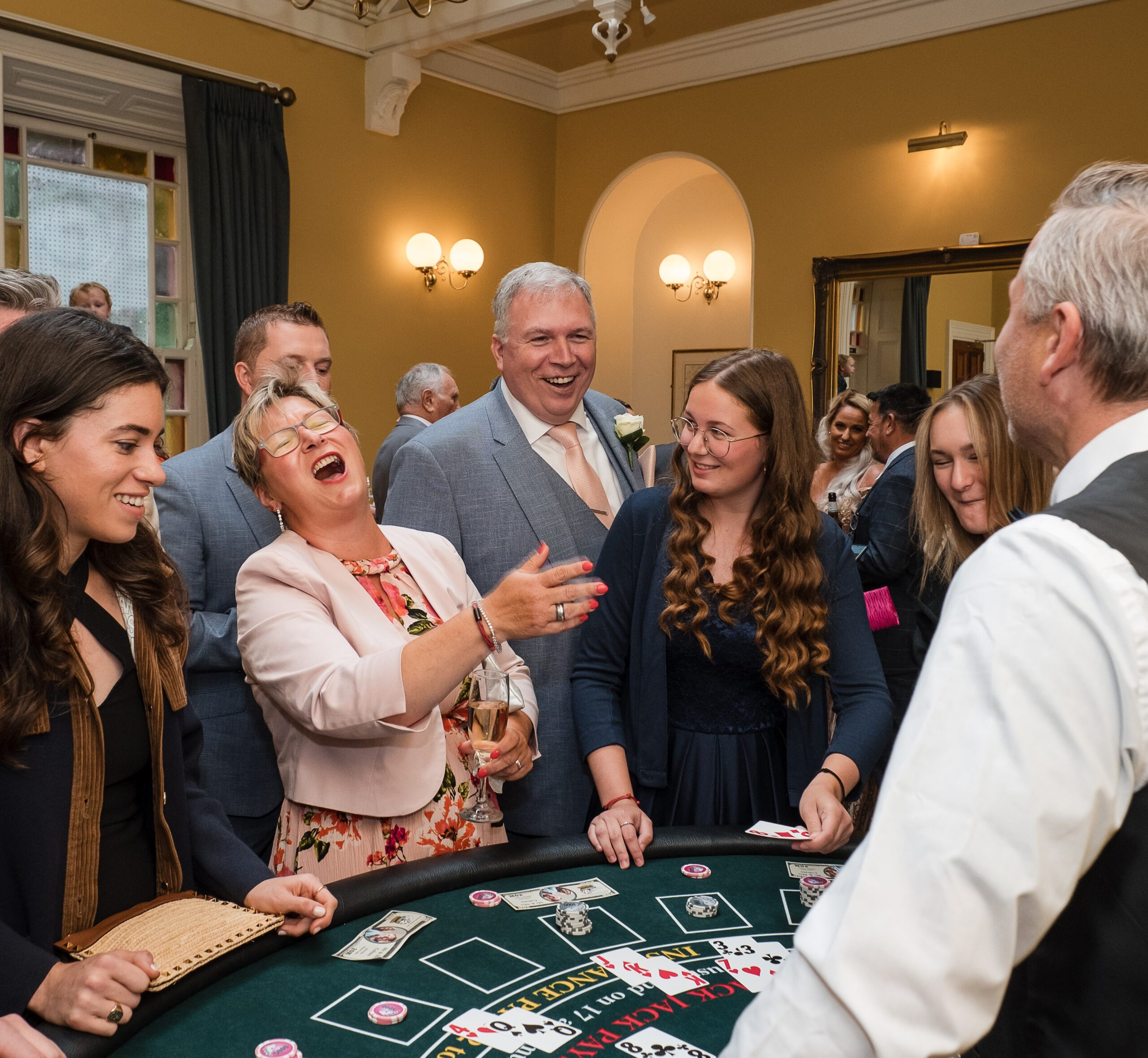 People gathered around a casino table, laughing and enjoying a festive event indoors.