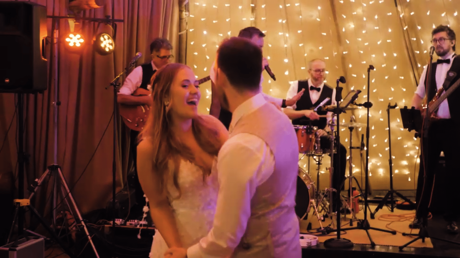 Bride and groom dancing at a wedding with a live band performing on stage.
