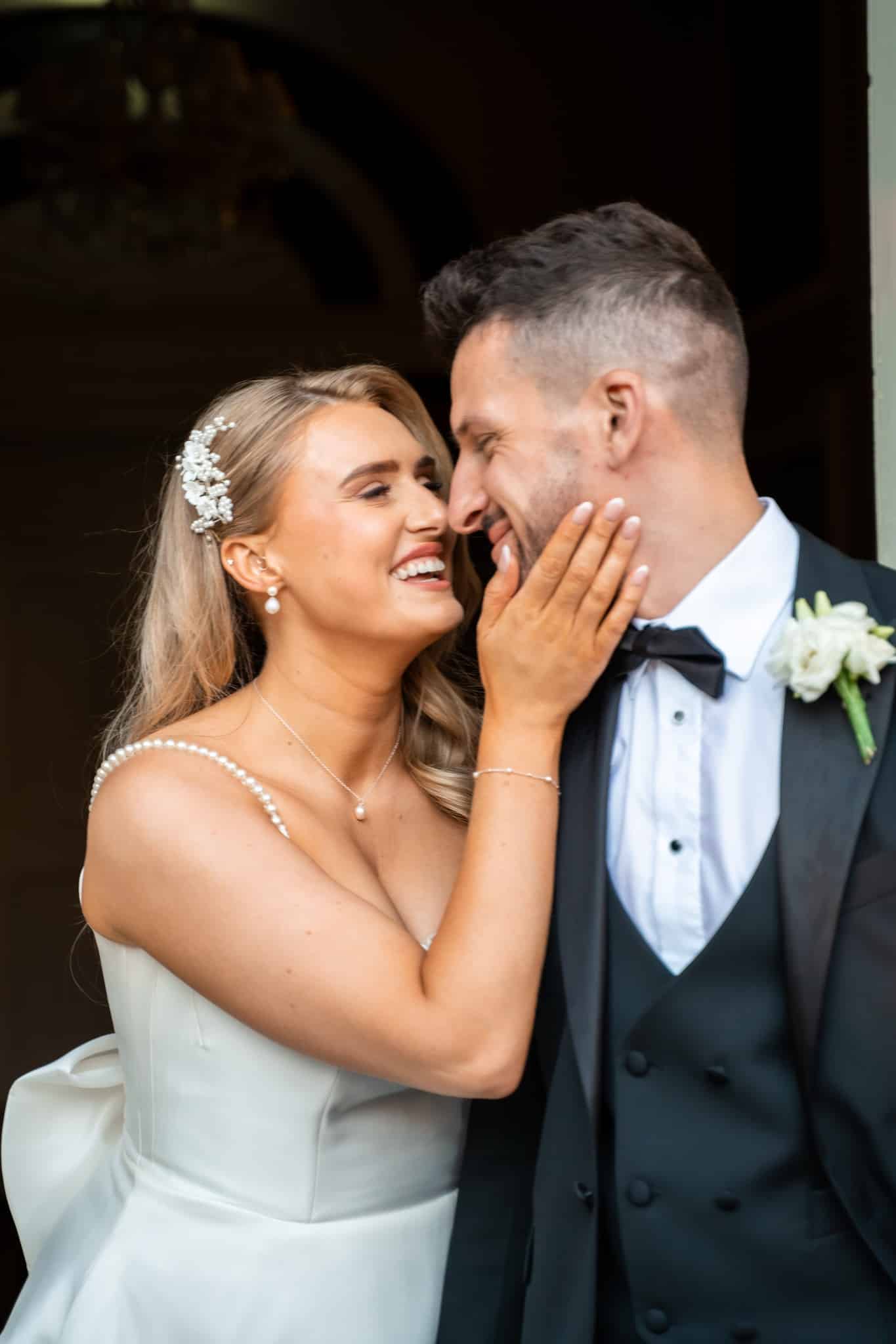 Bride and groom smiling affectionately in a close embrace.