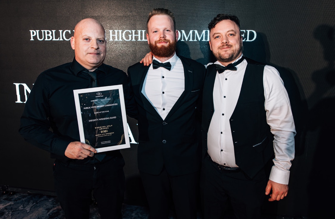 Three men in formal attire holding an award certificate in front of a backdrop.