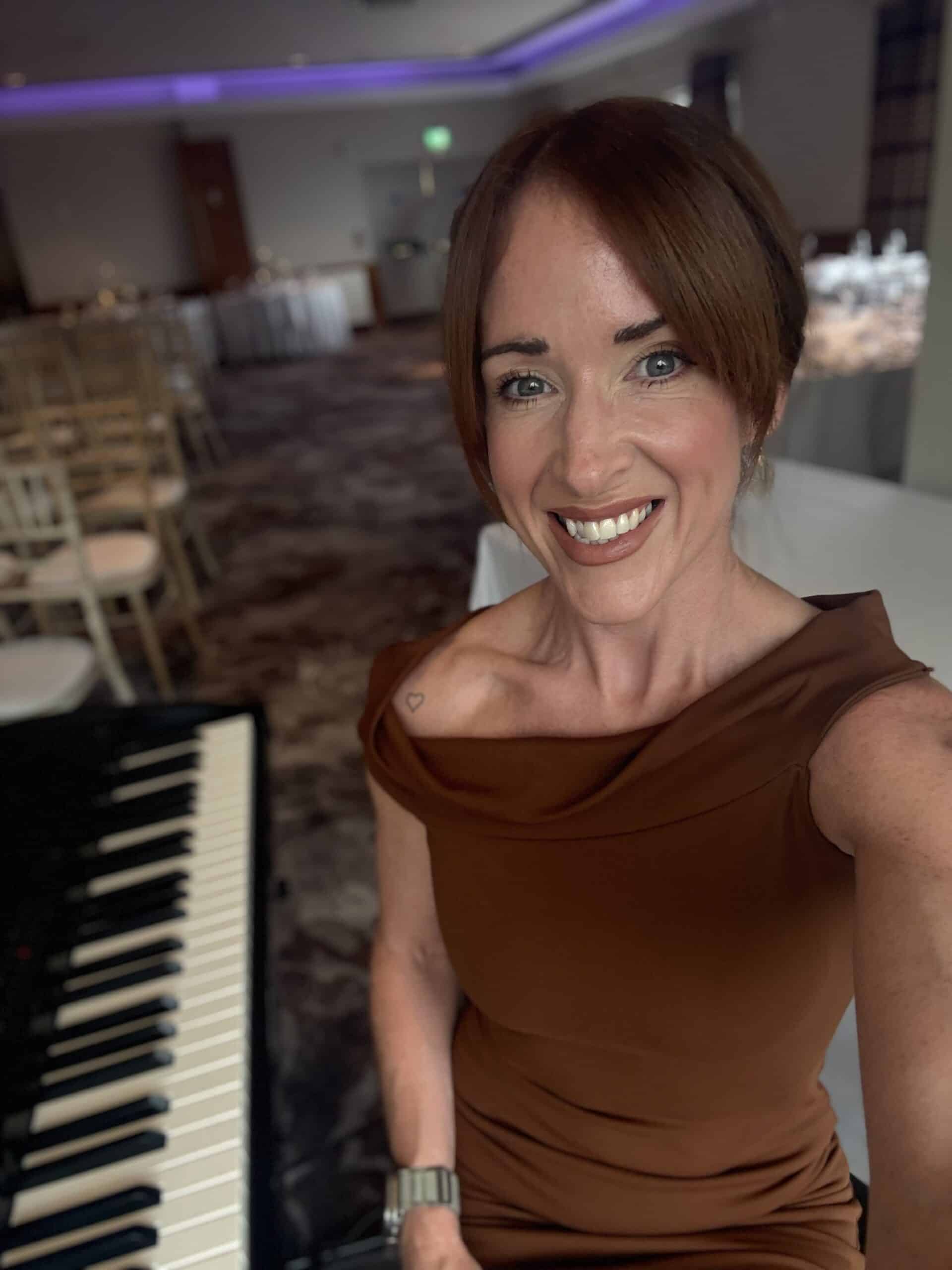 Woman smiling next to a piano in a decorated dining area.