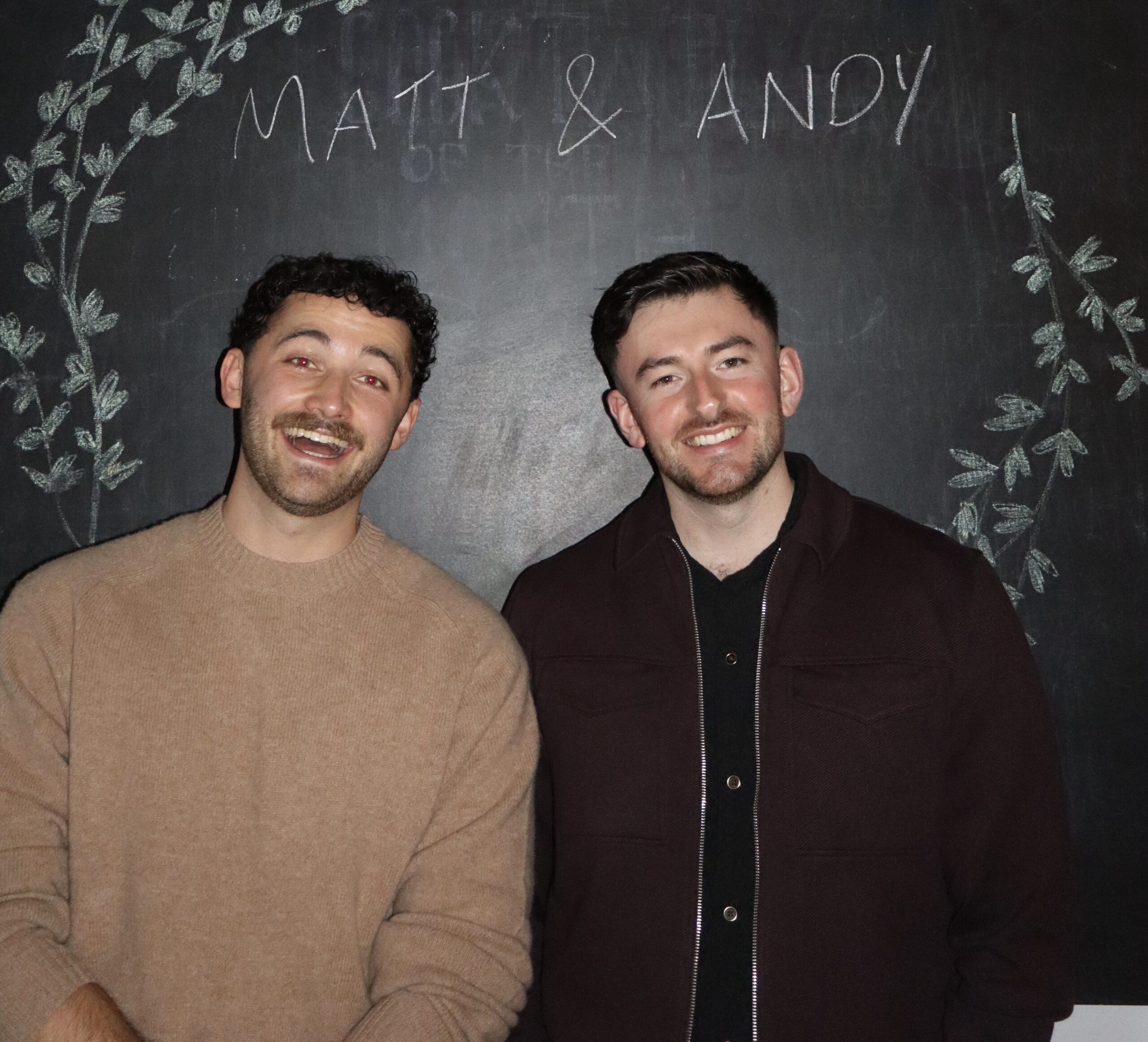 Two smiling men standing in front of a chalkboard with "Matt & Andy" written on it.