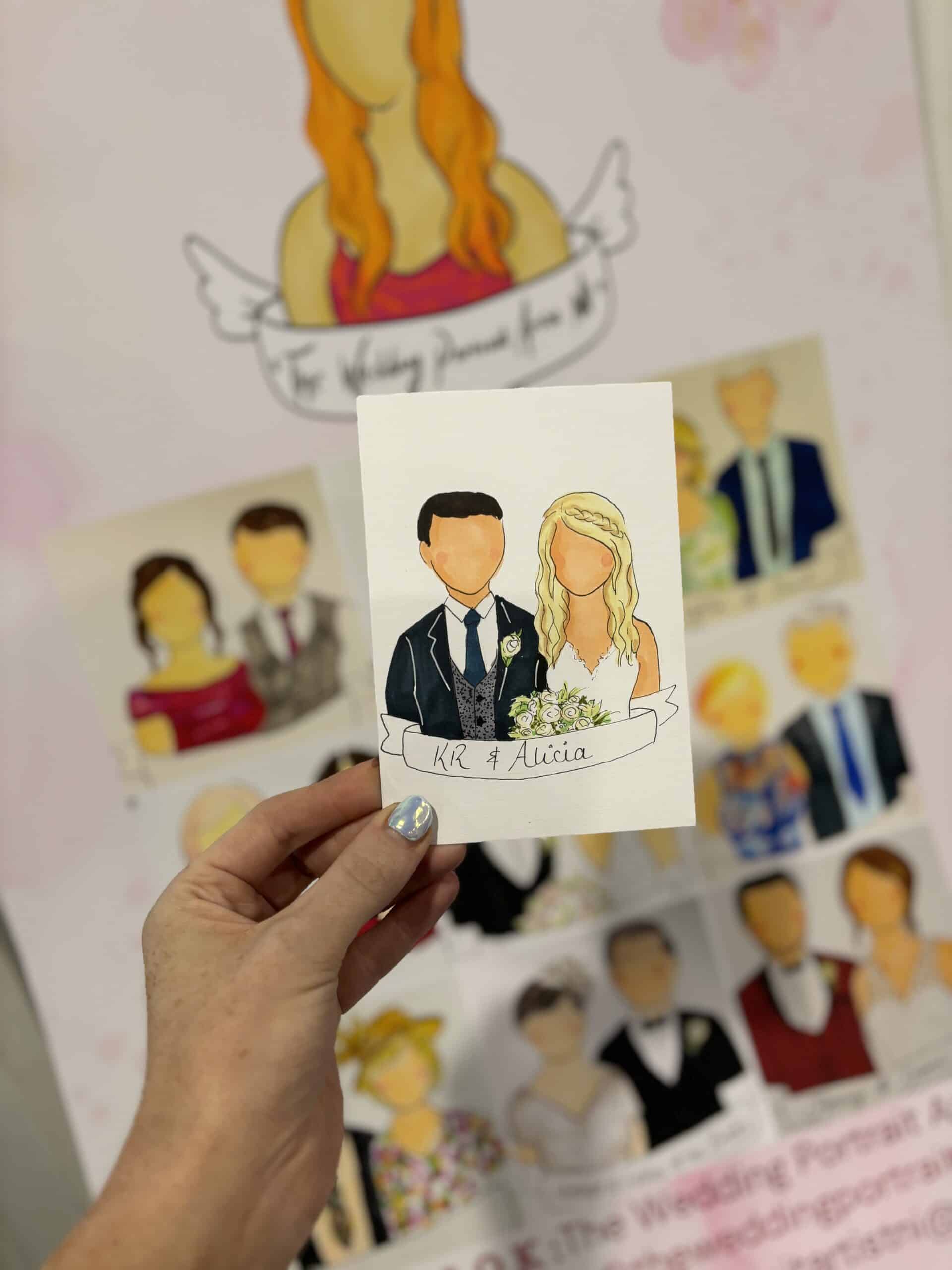 Hand holding a cartoon wedding portrait featuring a couple with a floral banner labeled "KR & Alicia," set against a background of similar portraits.