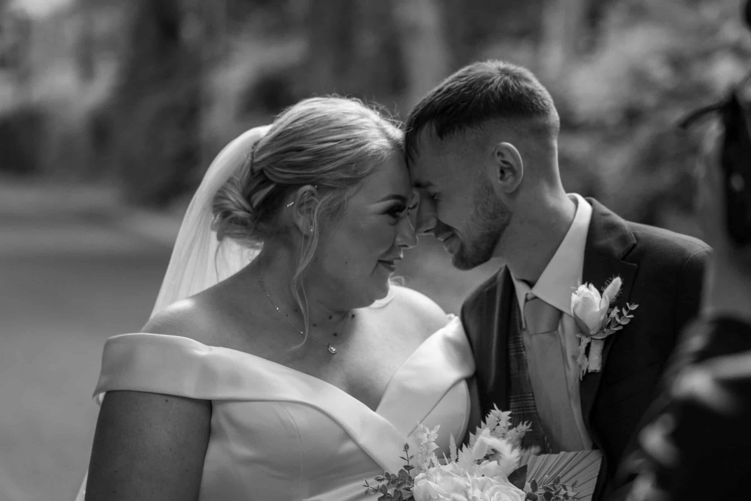 Bride and groom touching foreheads, sharing a joyful moment on their wedding day.