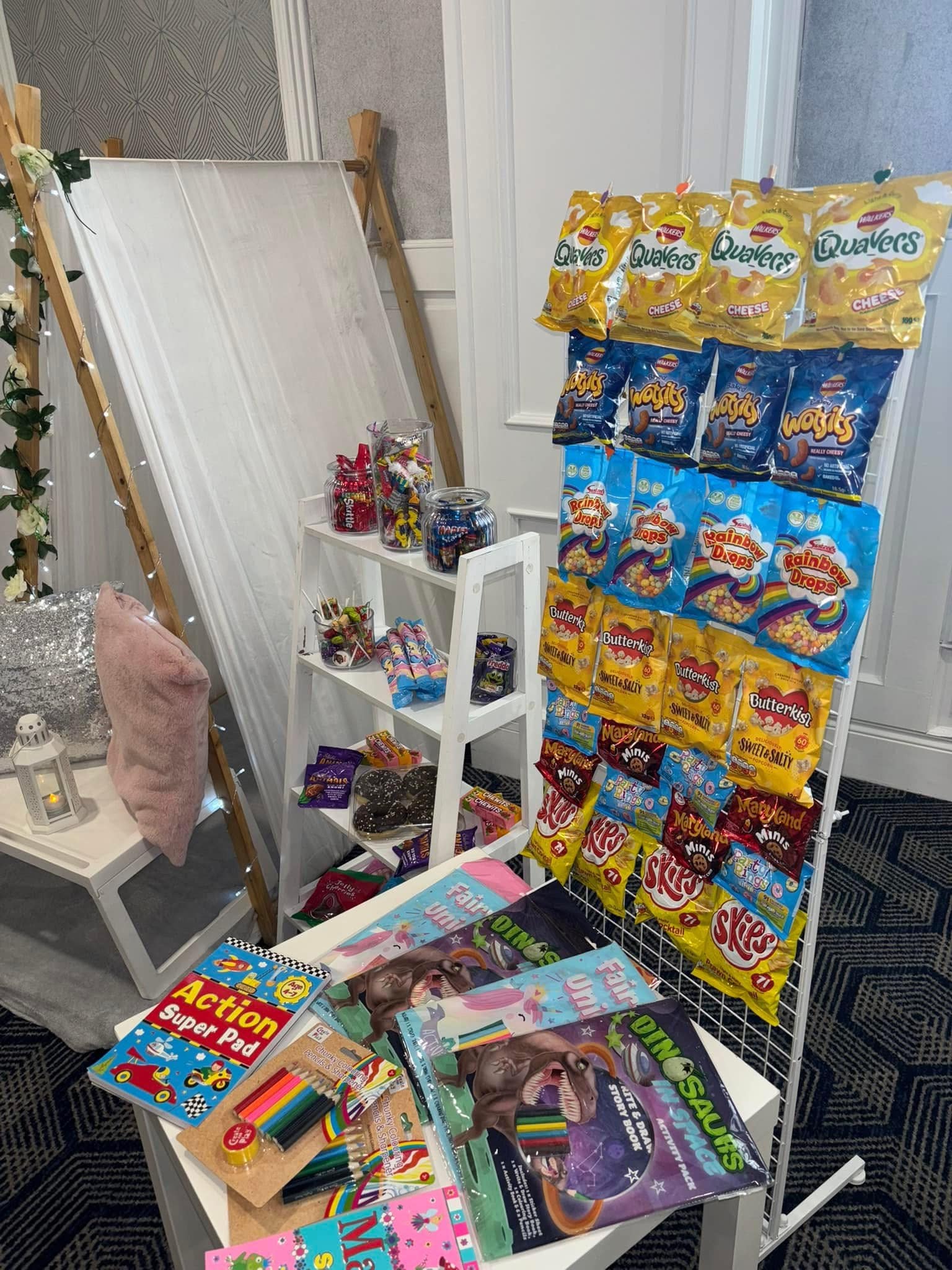 Snacks and activity books on display with a white backdrop and decorative lights.