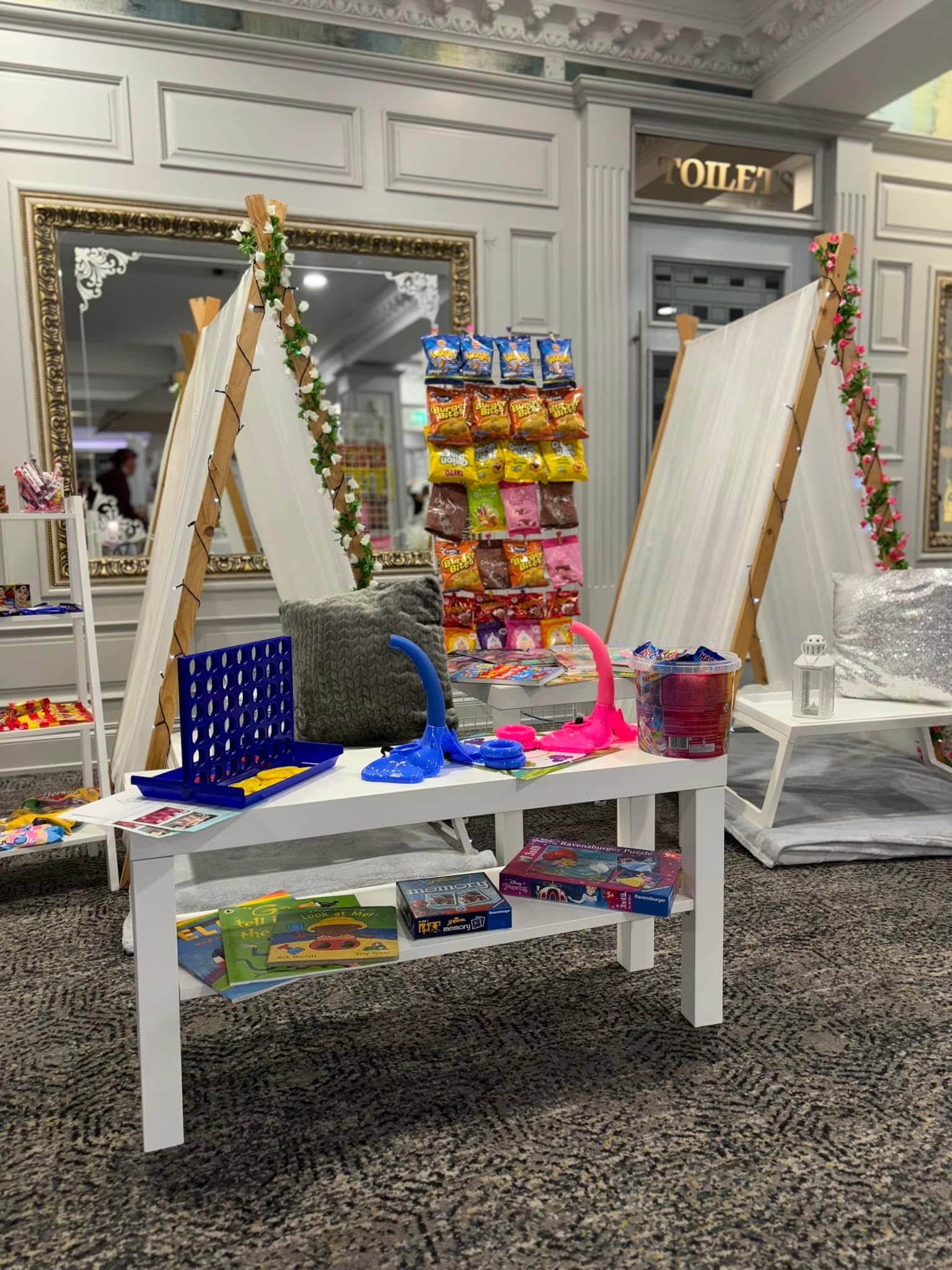 Indoor play area with games and snacks, featuring a Connect Four game, snacks display, and teepee tents.