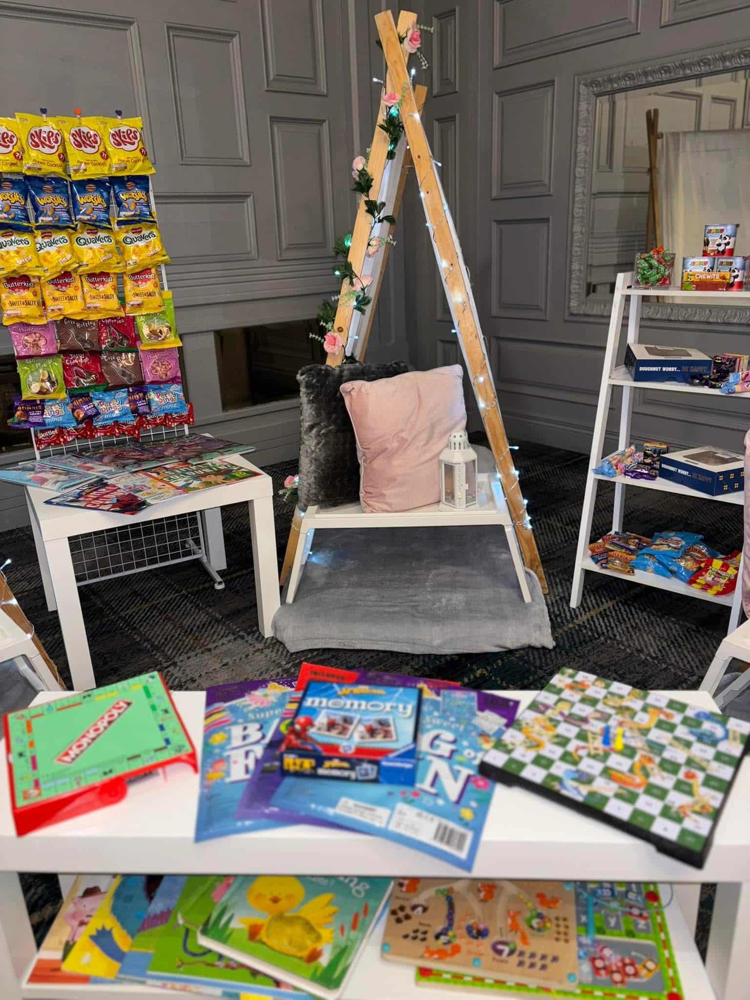 Display of children's games and snacks with a cozy reading nook and decorative ladder in a room setting.