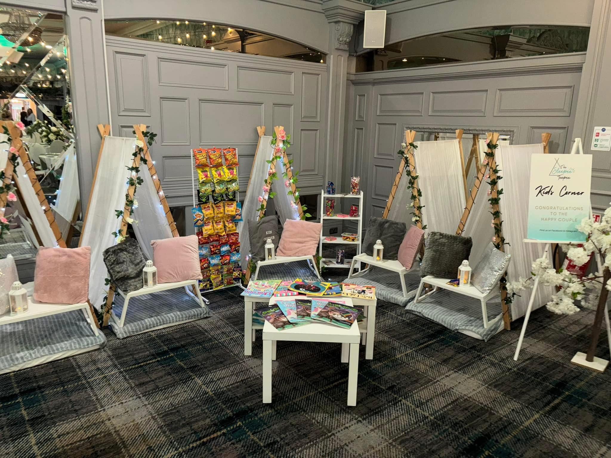 Indoor seating area with small tents, cushions, and snacks, alongside a congratulatory sign for a happy couple.