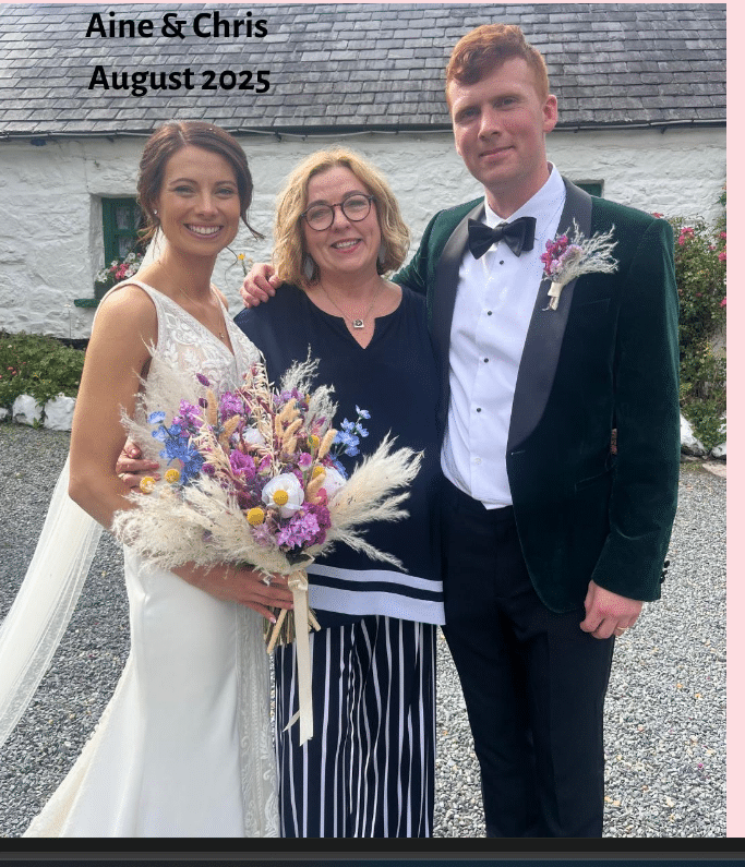 Bride and groom with a guest, posing outdoors at a wedding, August 2025.