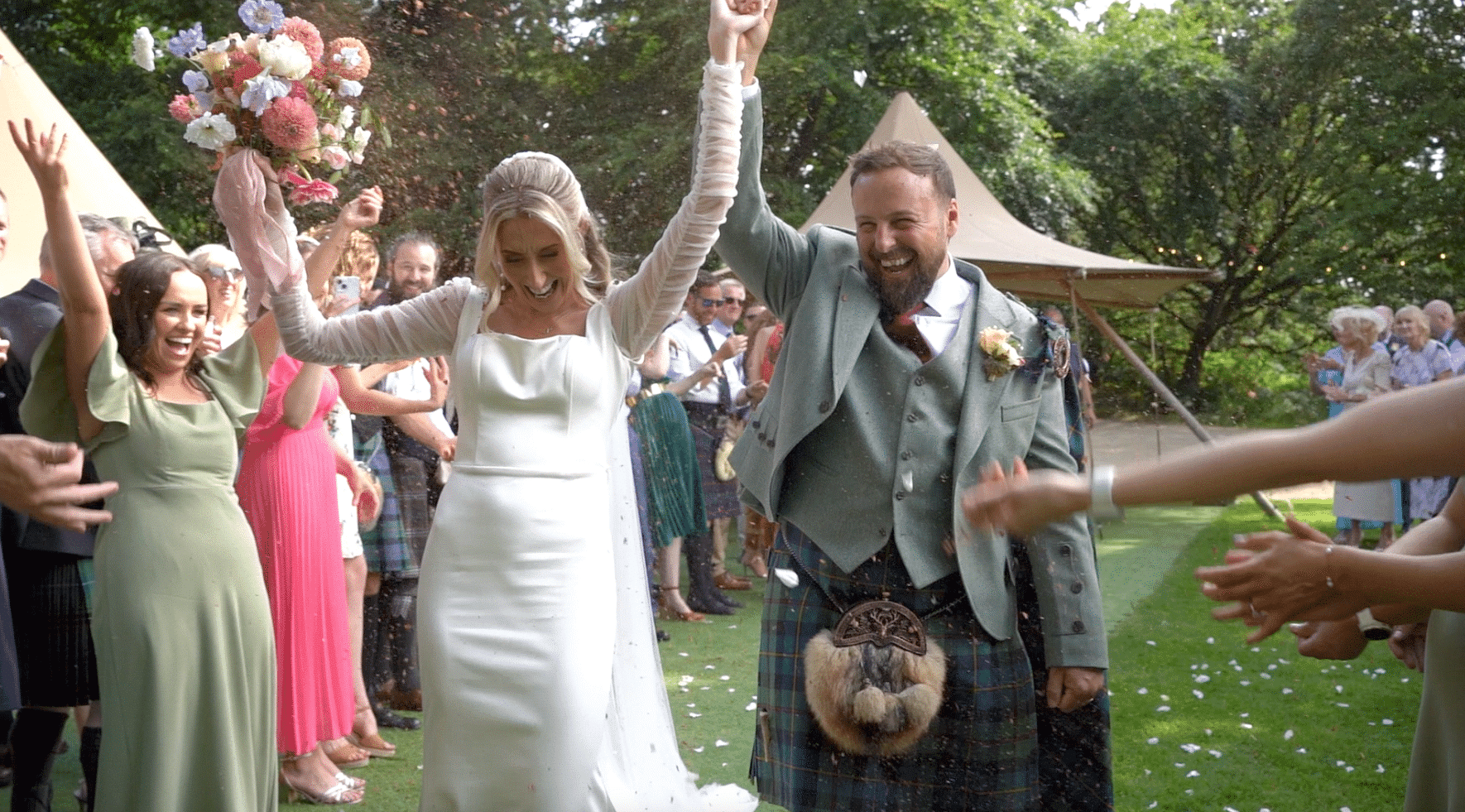 Bride and groom celebrating outdoors, surrounded by guests, with confetti in the air.