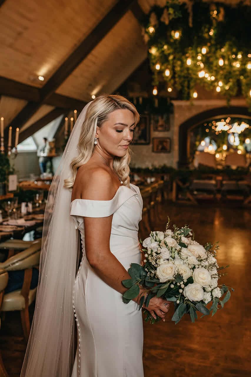 Bride holding a bouquet in a dimly lit, elegant venue.