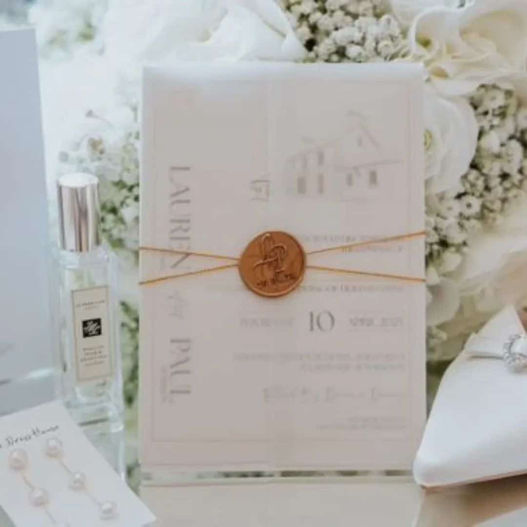 Elegant wedding invitation set with floral background, perfume bottle, and pearl accessories.