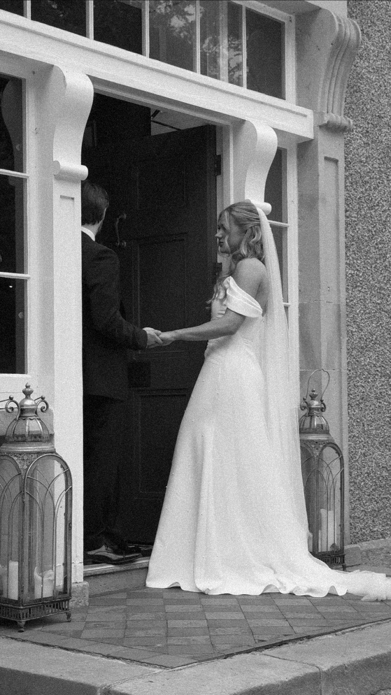Bride and groom holding hands at a doorway, black and white photo.