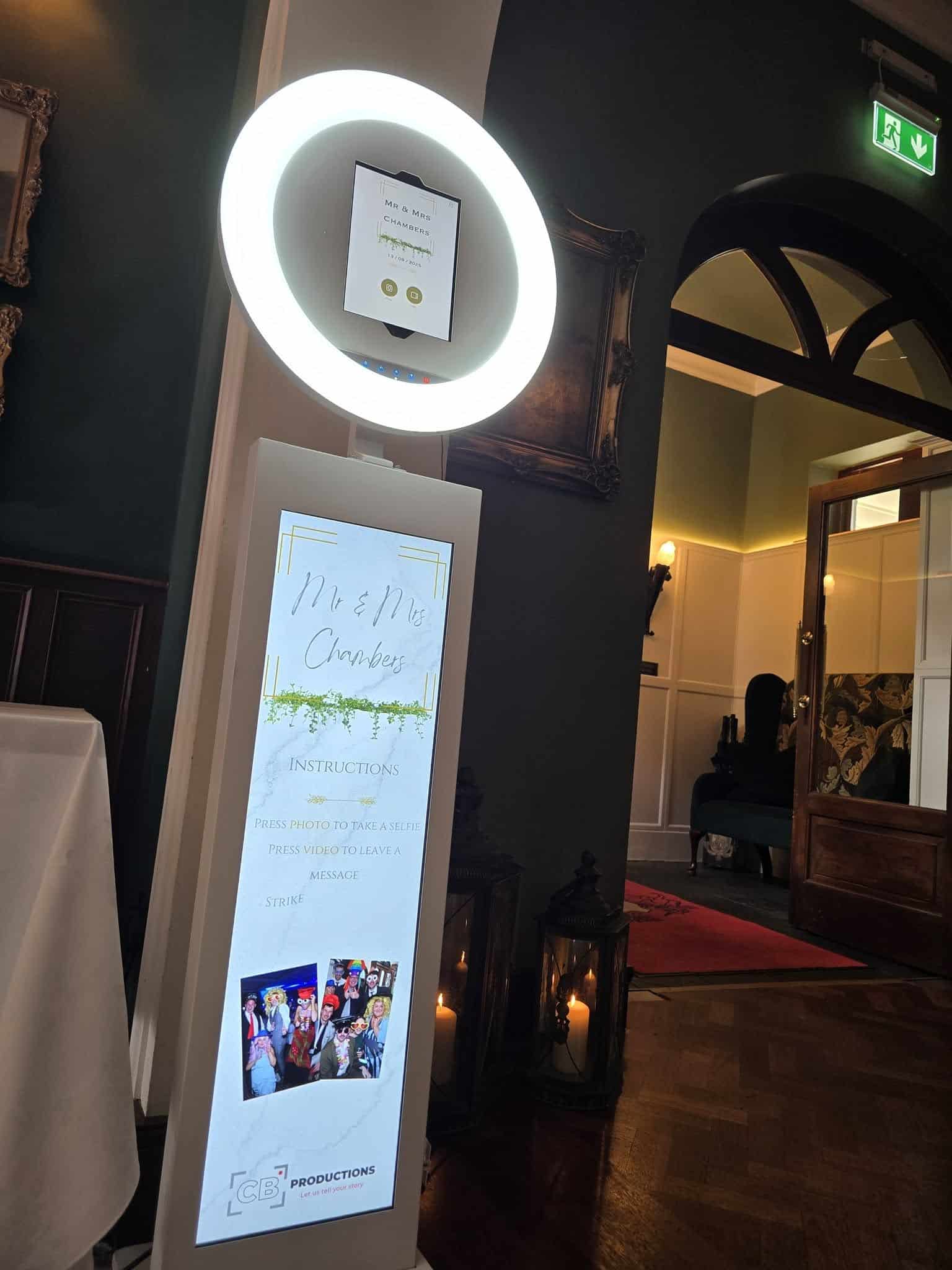 Interactive photo booth with glowing ring light and instructions for a wedding event.