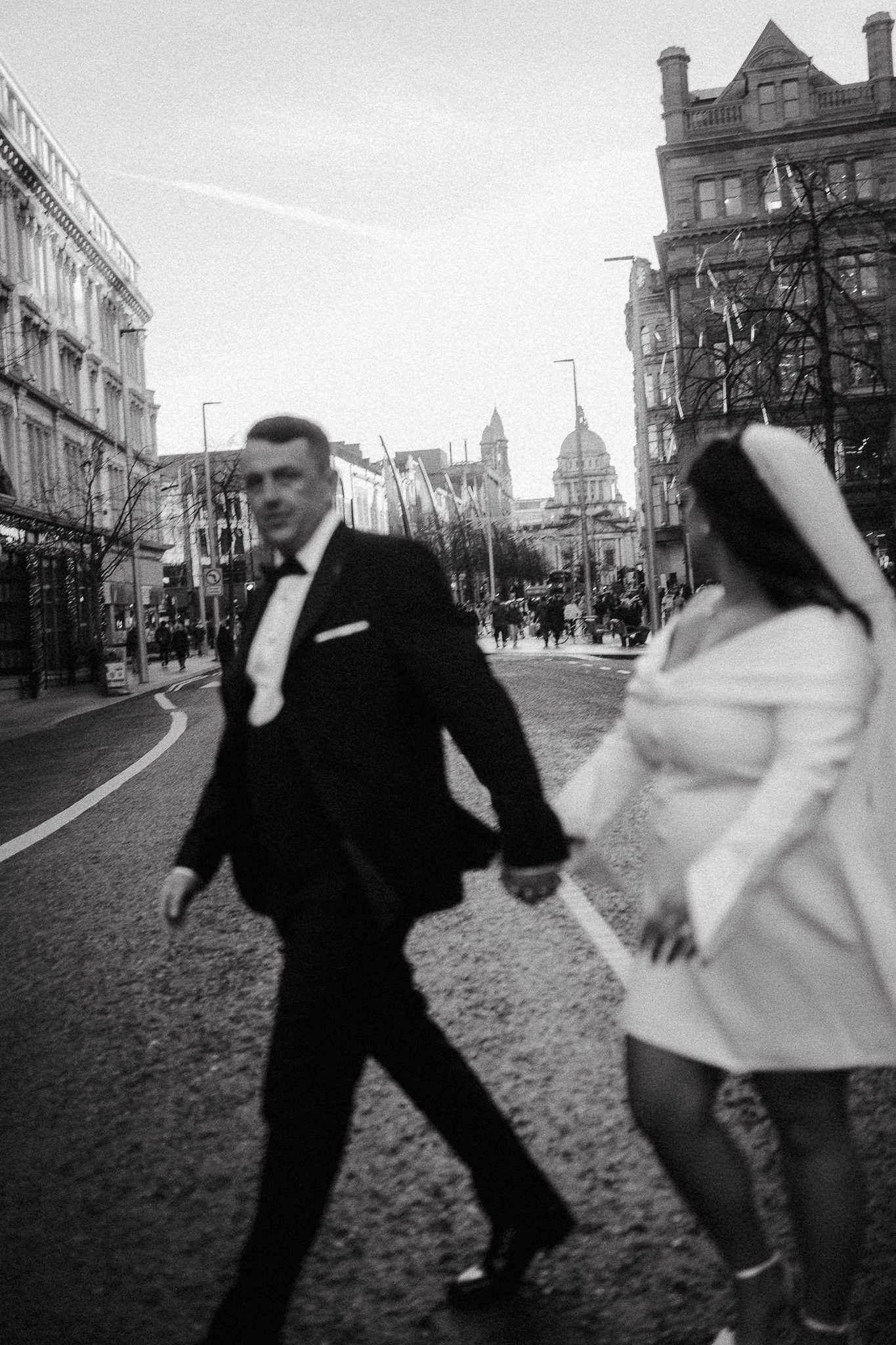 Couple holding hands, walking on a city street in black and white.