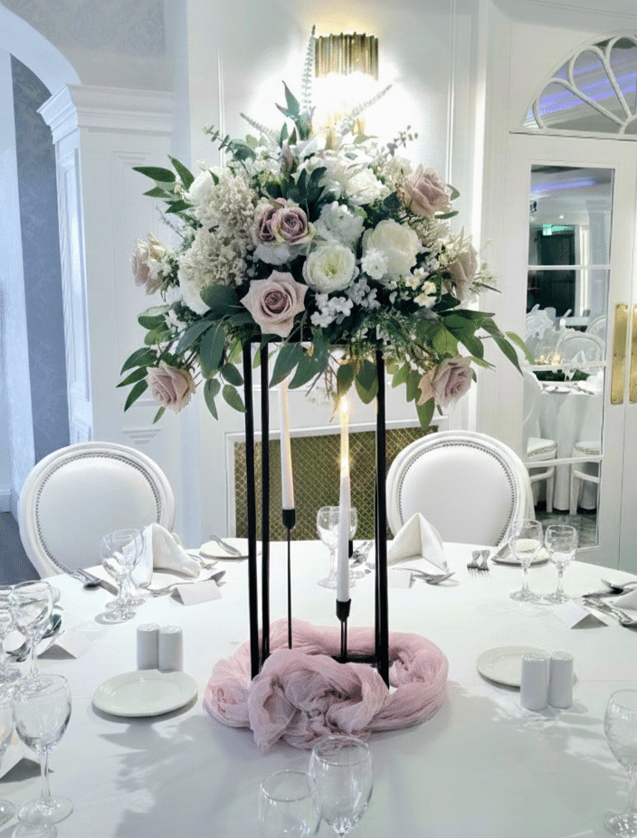 Elegant floral centerpiece with pink and white roses on a decorated wedding reception table.