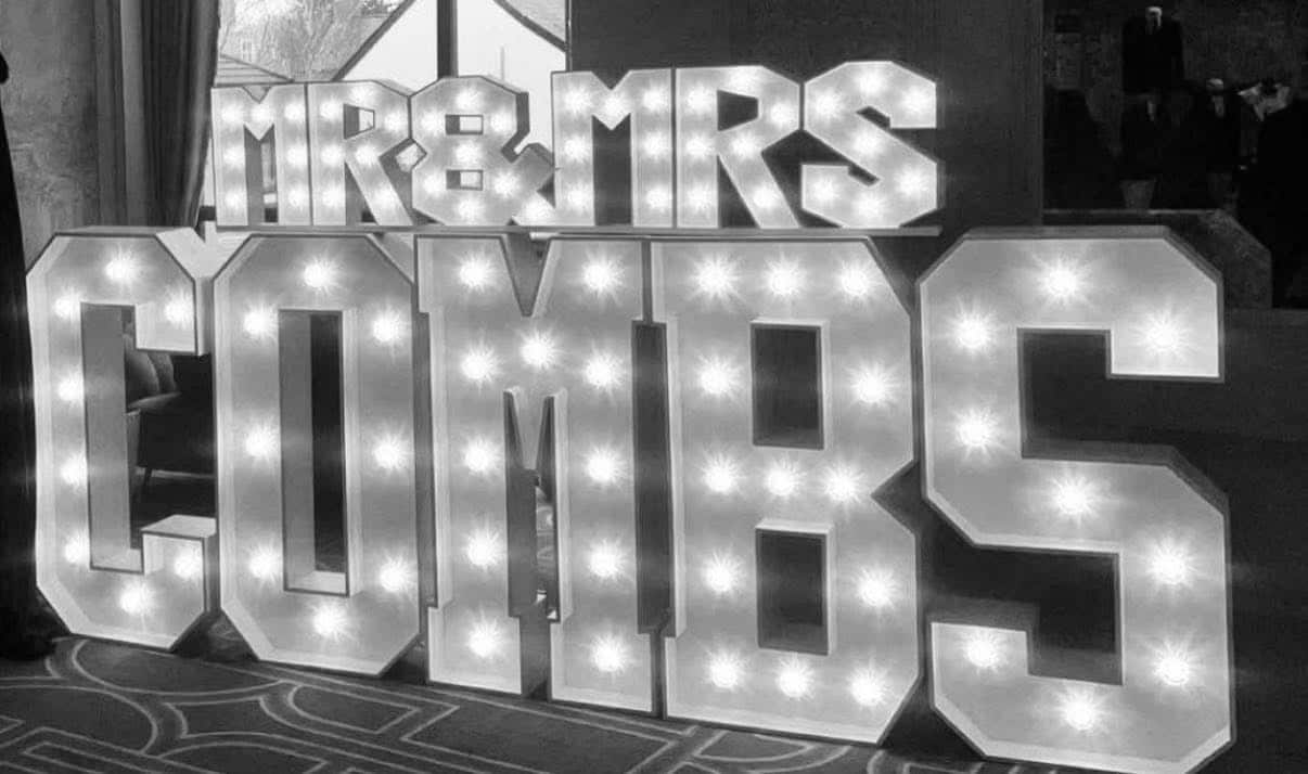 Illuminated "Mr & Mrs Combs" sign in a dimly lit room.