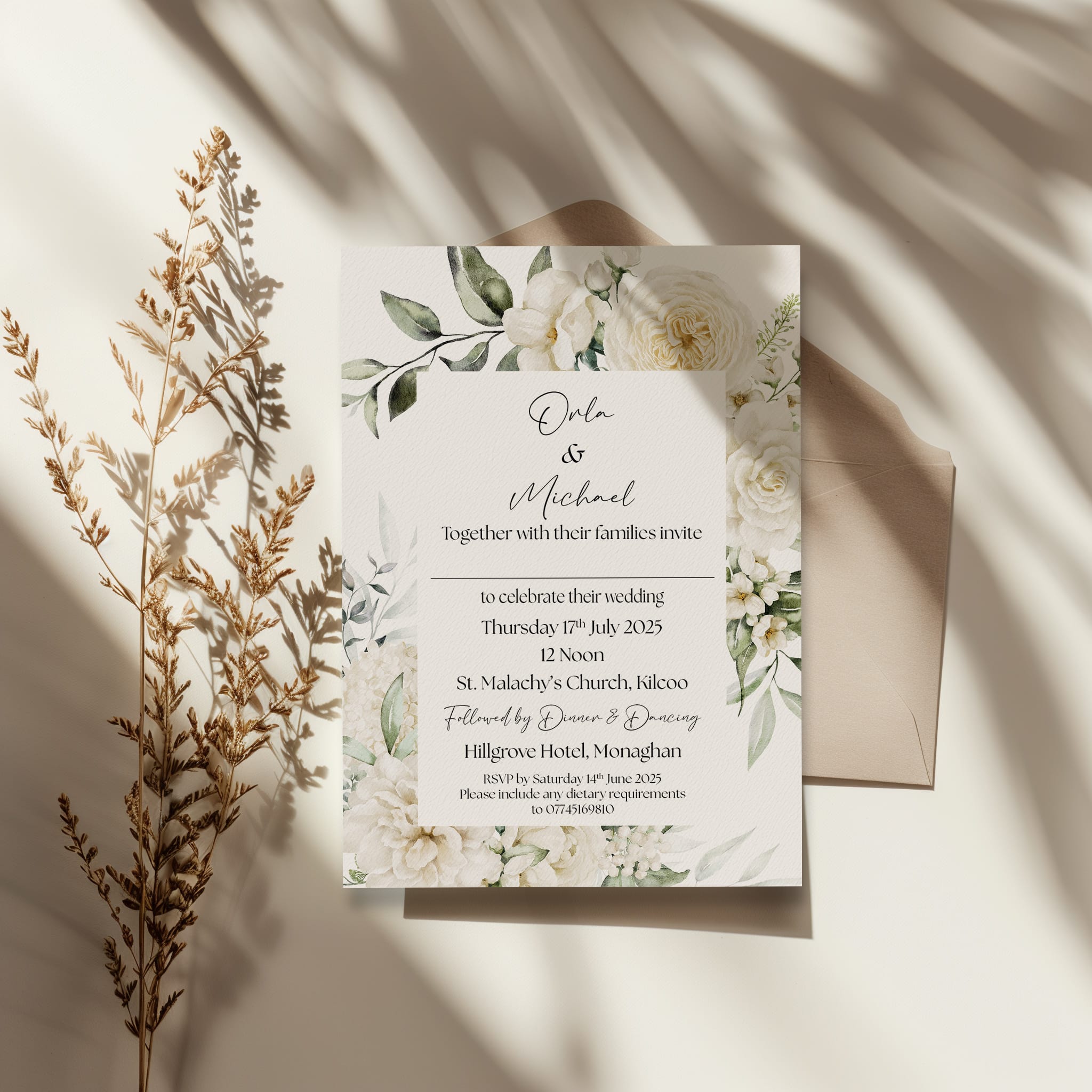 Elegant wedding invitation with floral design and an envelope on a light surface with shadow play.