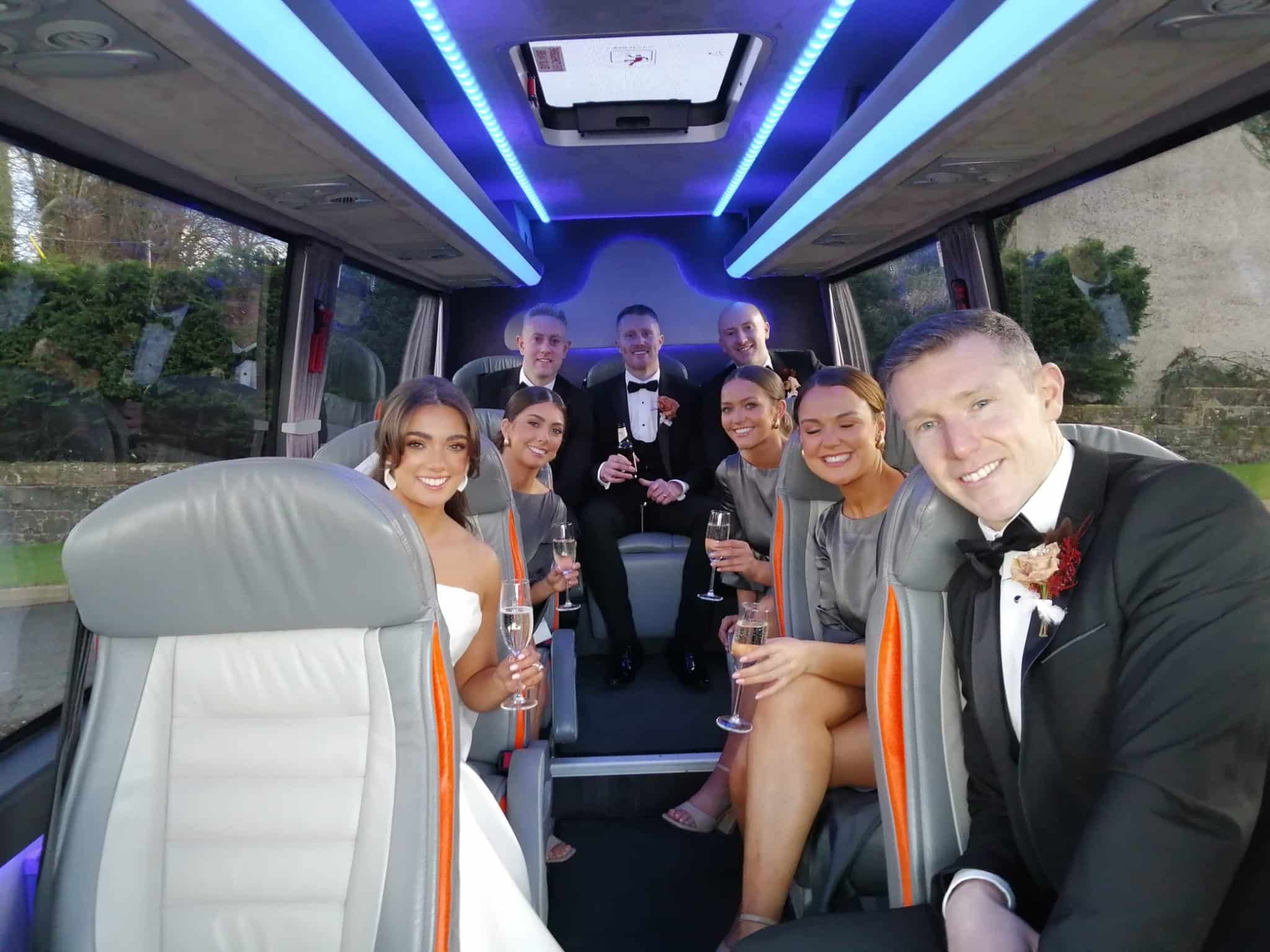 Group of elegantly dressed people smiling inside a limo, holding champagne glasses.