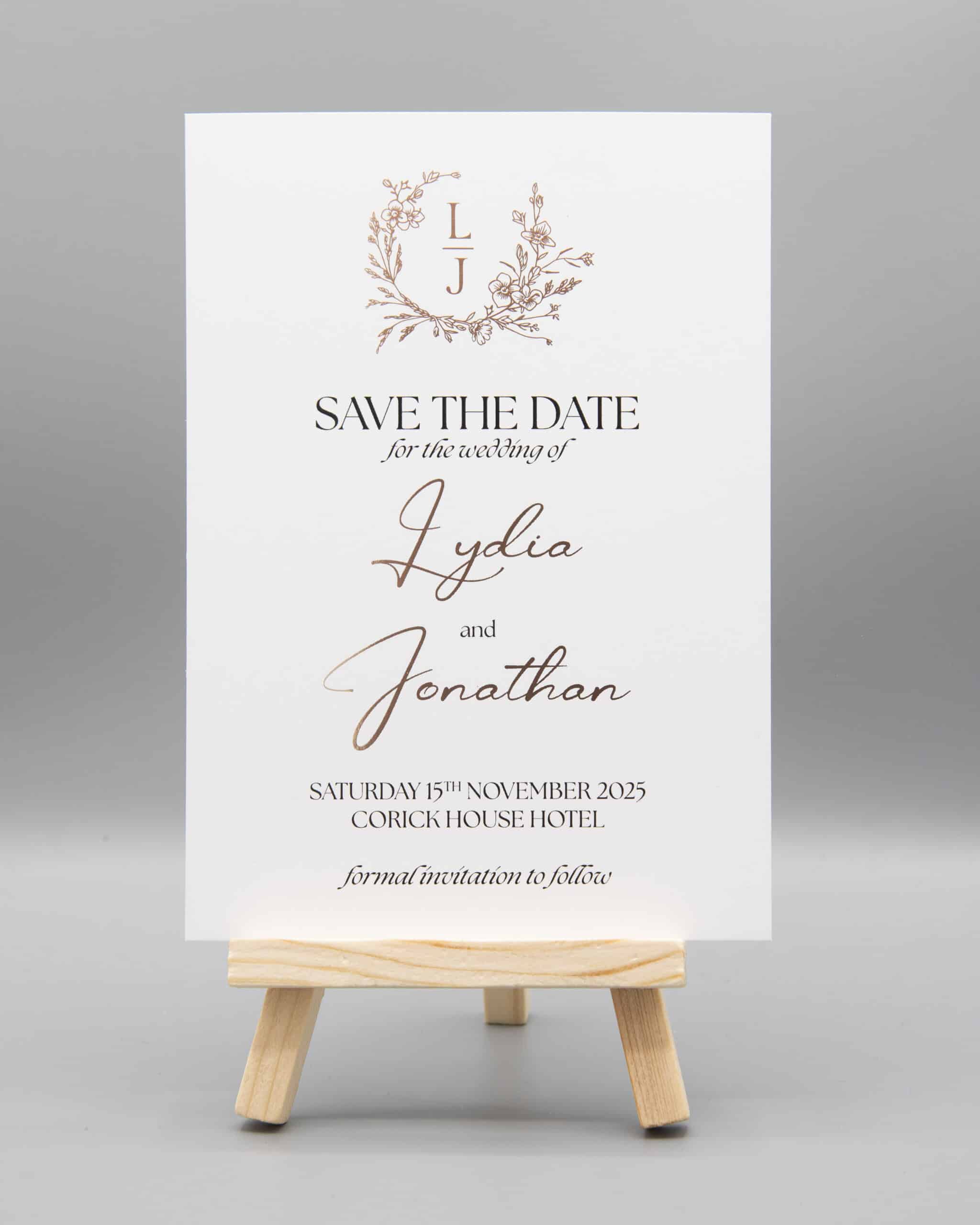 Save the date wedding card on a wooden easel, announcing Lydia and Jonathan's wedding on November 15, 2025, at Corick House Hotel.