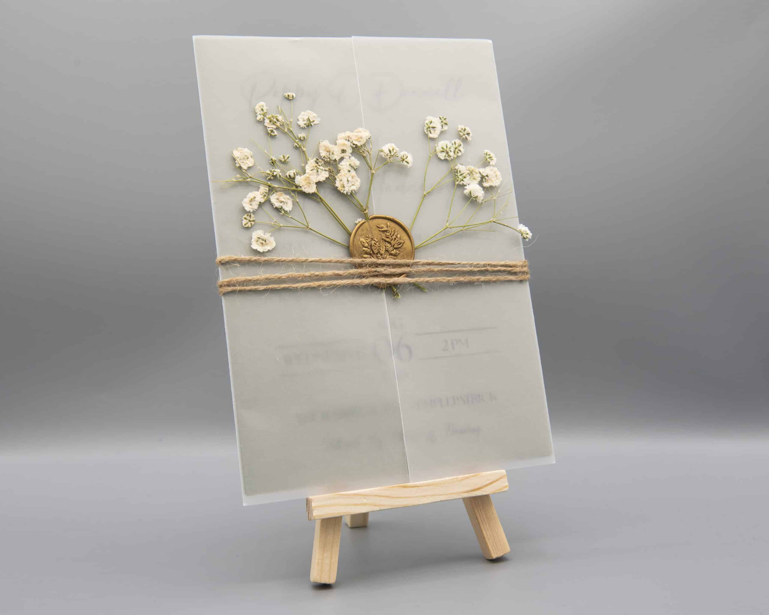 Elegant invitation card with floral design on a small wooden easel.
