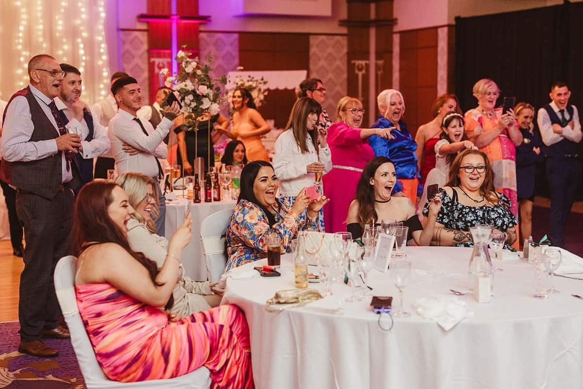 Group of people laughing and applauding at an indoor celebration.