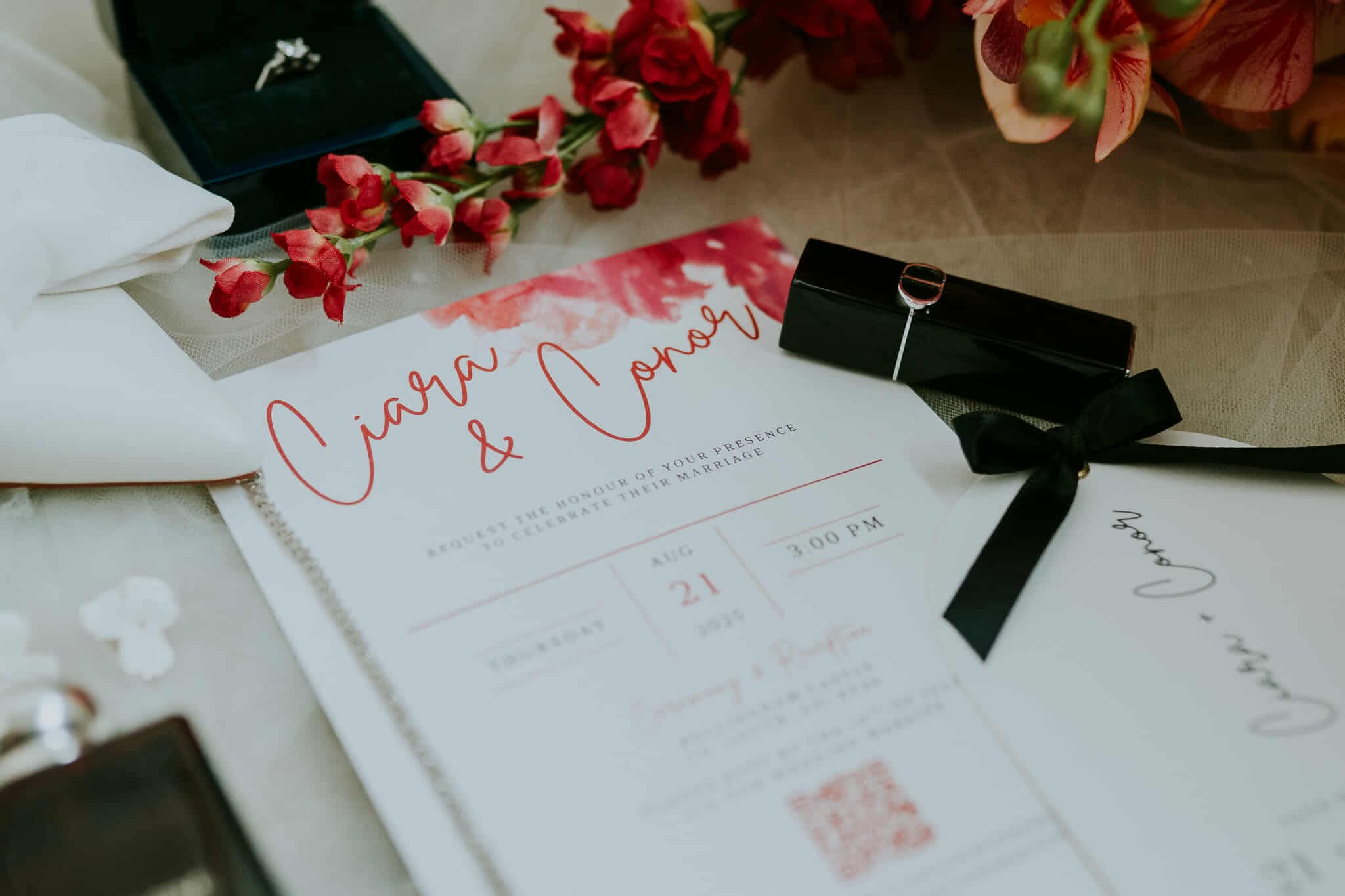 Wedding invitation with floral accents, jewelry box, and ring, featuring names Ciara and Conor.