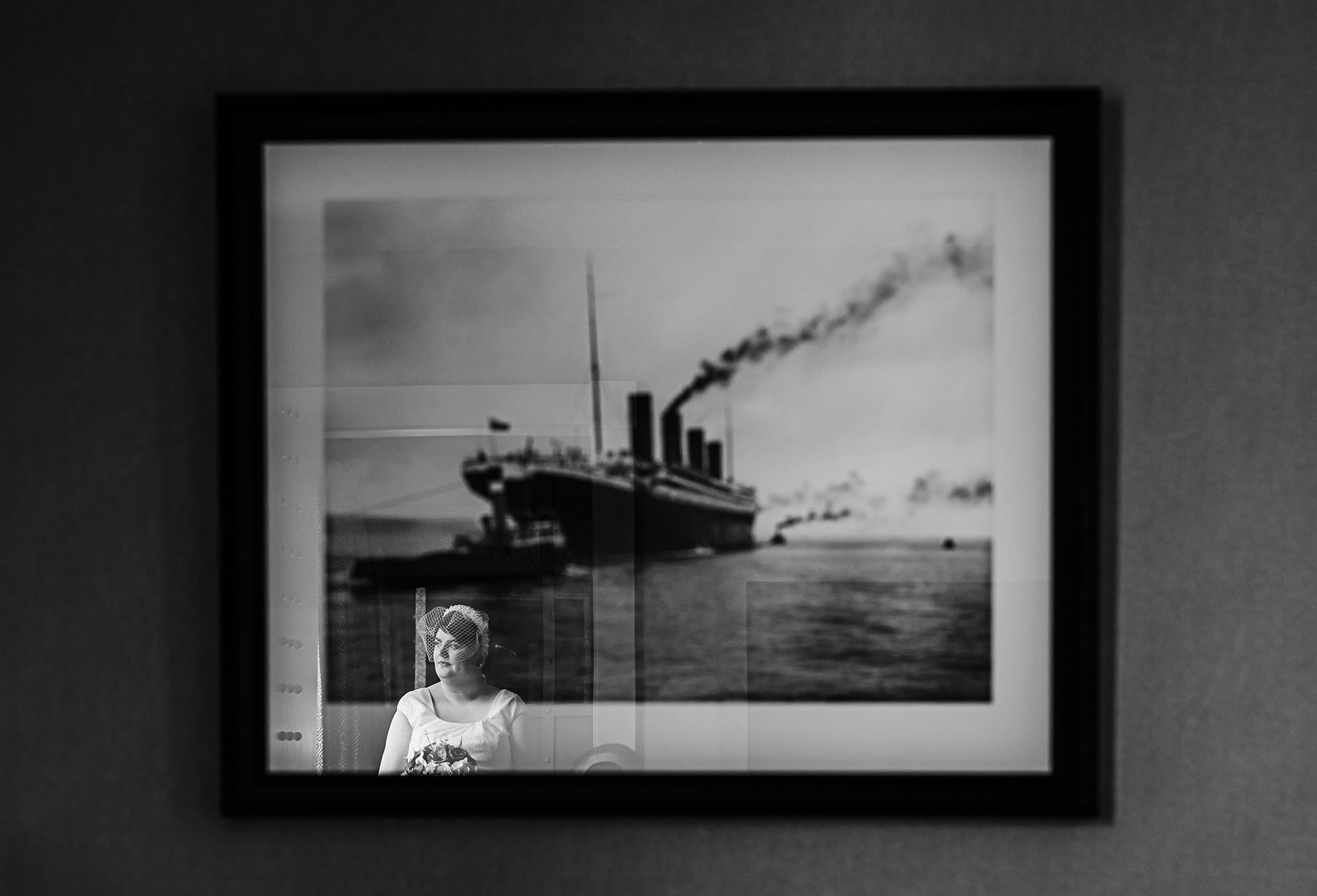 Black and white photo reflection of a bride under a framed Titanic print.