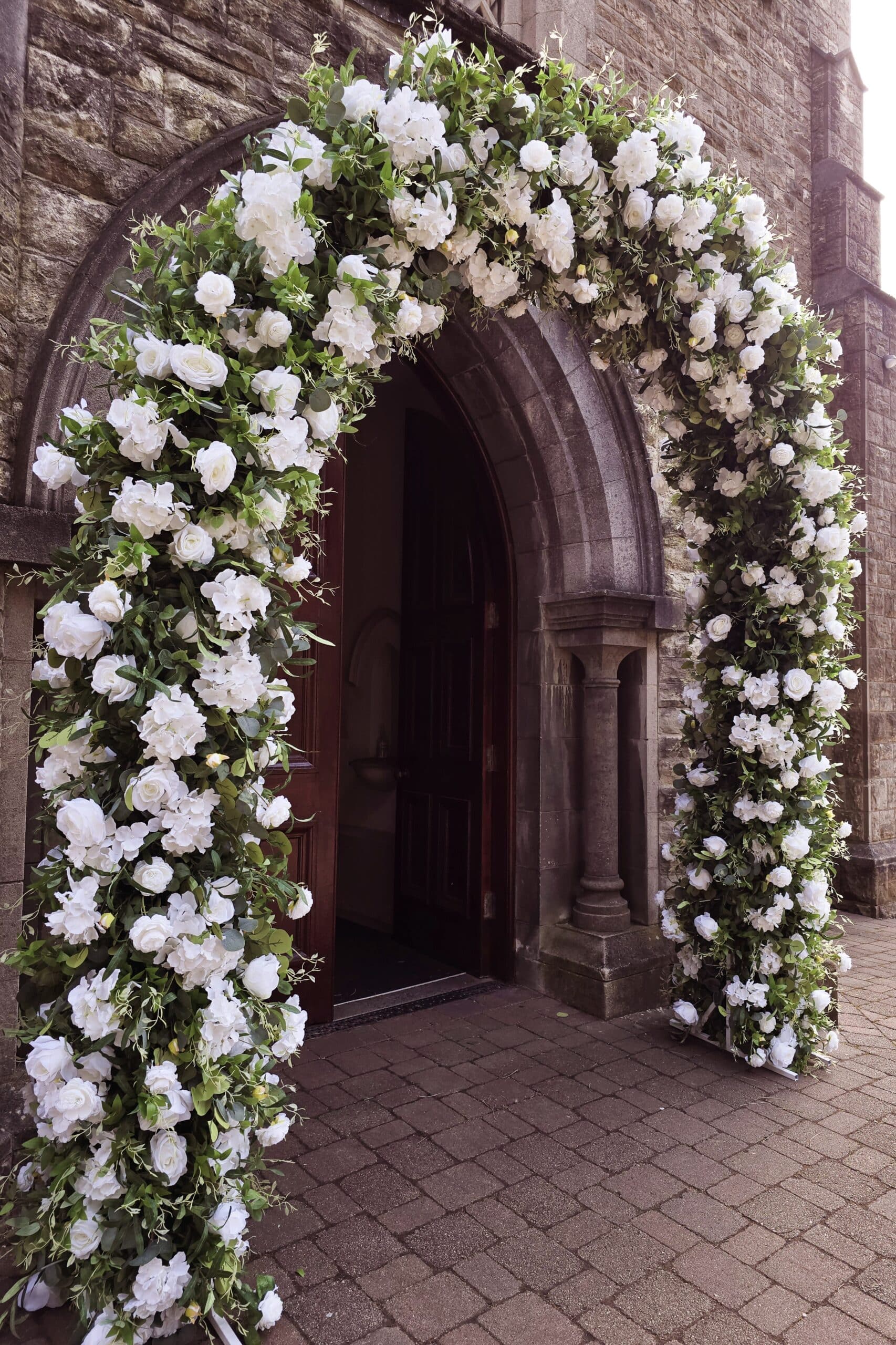 Stone archway adorned with white flower garland at building entrance.