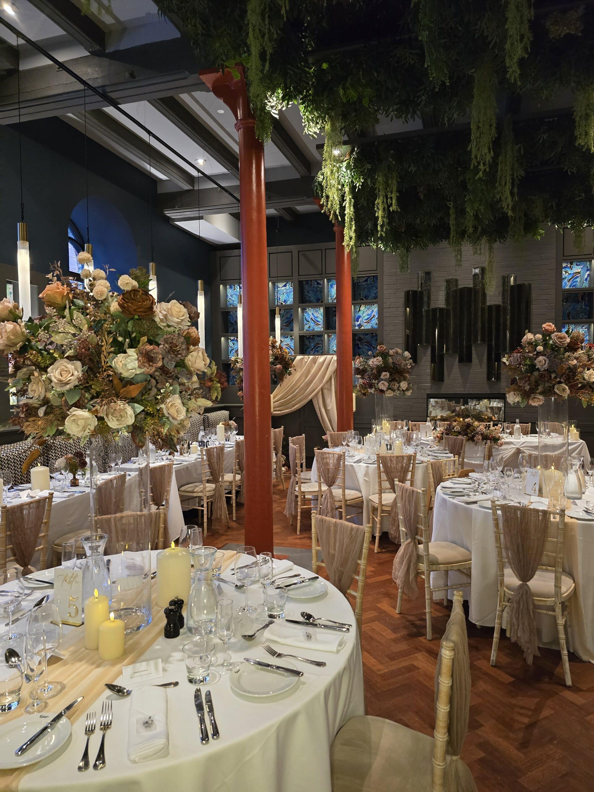 Elegant banquet hall with decorated tables, floral arrangements, and soft lighting.