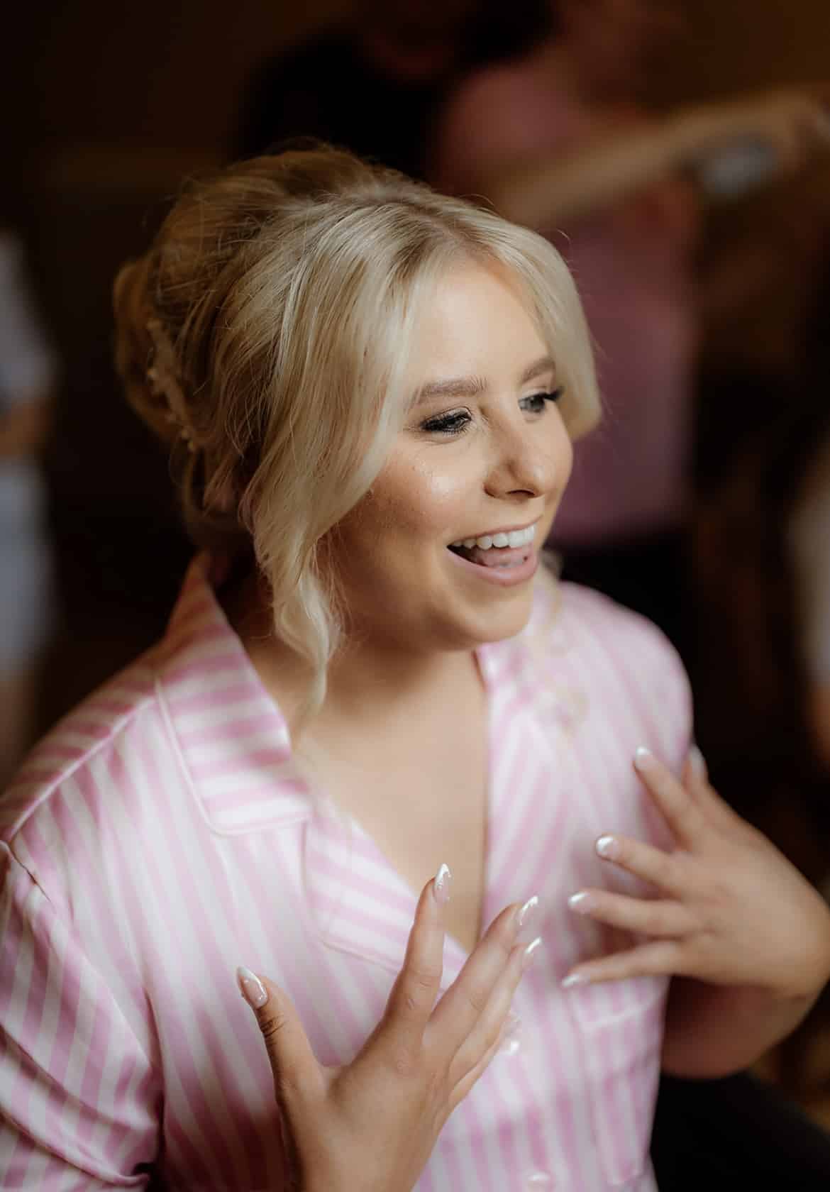 Smiling woman with blonde hair in a striped pink pajama top.